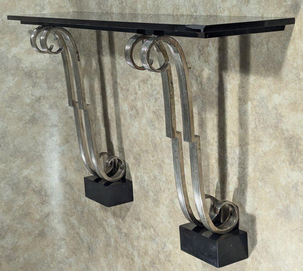 Console modernista francese in acciaio cromato o bronzo di Raymond Subes. Questa console presenta il piano originale in marmo nero e i piedistalli che si trovano sotto le basi. Circa 1930. La console misura 60