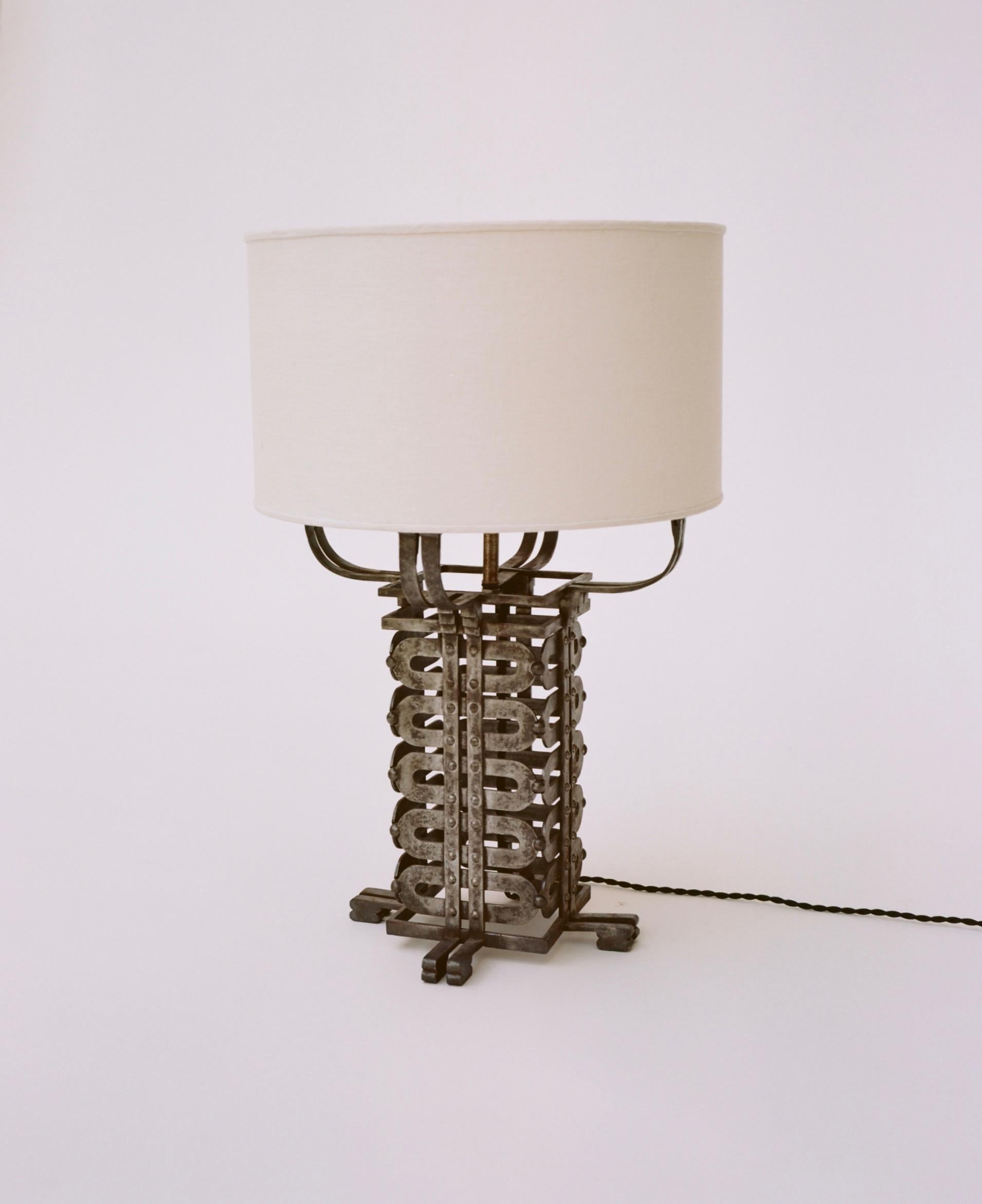 A silver-gilt wrought iron table lamp with cream colored linen shade. Rewired for US outlets and fitted with a custom ivory silk linen shade and cord. Exemplary of the more elaborate, art deco period with far eastern influences. Measurements with