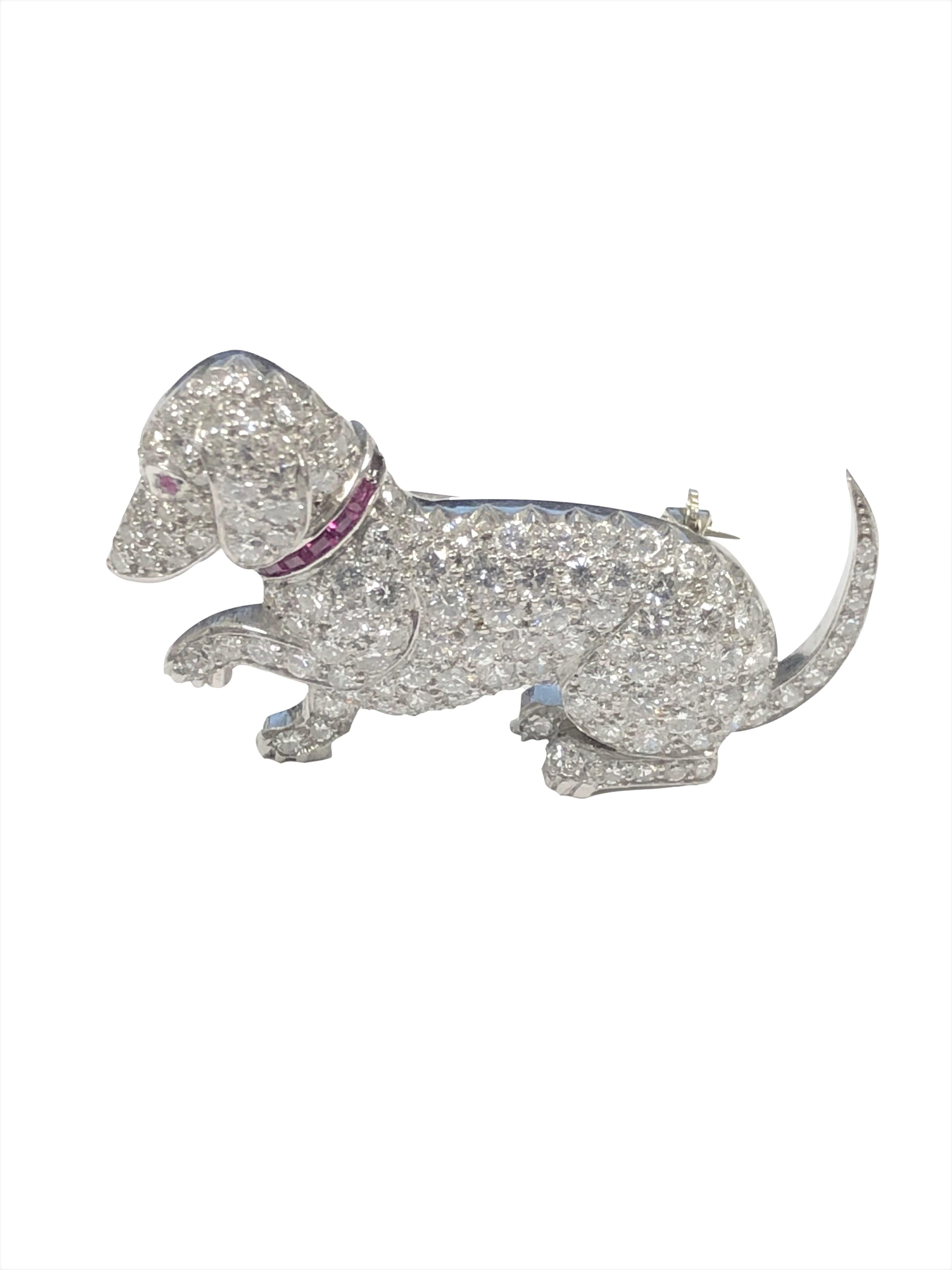 Circa 1930s Raymond C. Yard Platinum Dachshund Dog Brooch, measuring 1 3/8 inch in length X 3/4 inch. Set with Fine White Transitional cut Diamonds totaling 3 1/2 Carats. Further set with Baguette Rubies forming a Dog Collar and a Ruby set Eye.