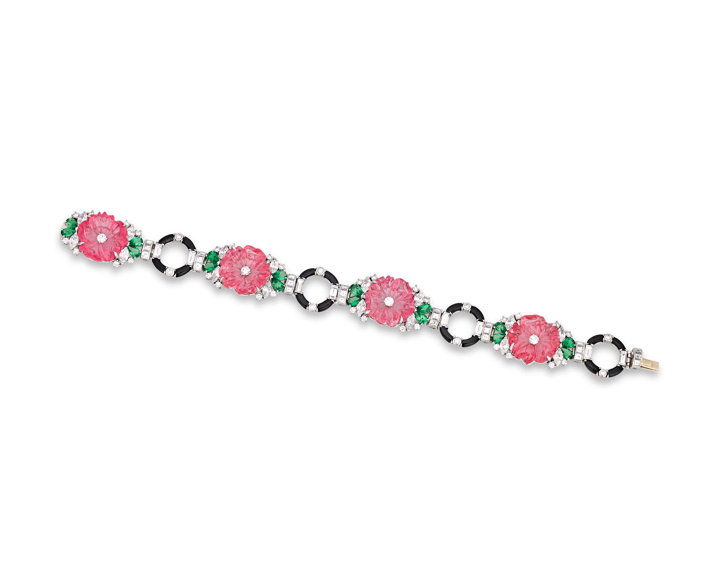 Tourmaline flowers bloom in this stunning carved gemstone bracelet by Raymond Yard. The flowers display a vivid shade of pink, while green tsavorites are carved to form leaves. Marquise, baguette, square and round-cut diamonds set along the length