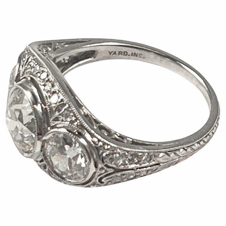Exquisite handmade platinum and diamond ring by Raymond Yard from the Edwardian period, circa 1910. Set with three old European-cut diamonds and small diamond accents throughout. Center diamond weighing approximately 1.61 carats flanked by side