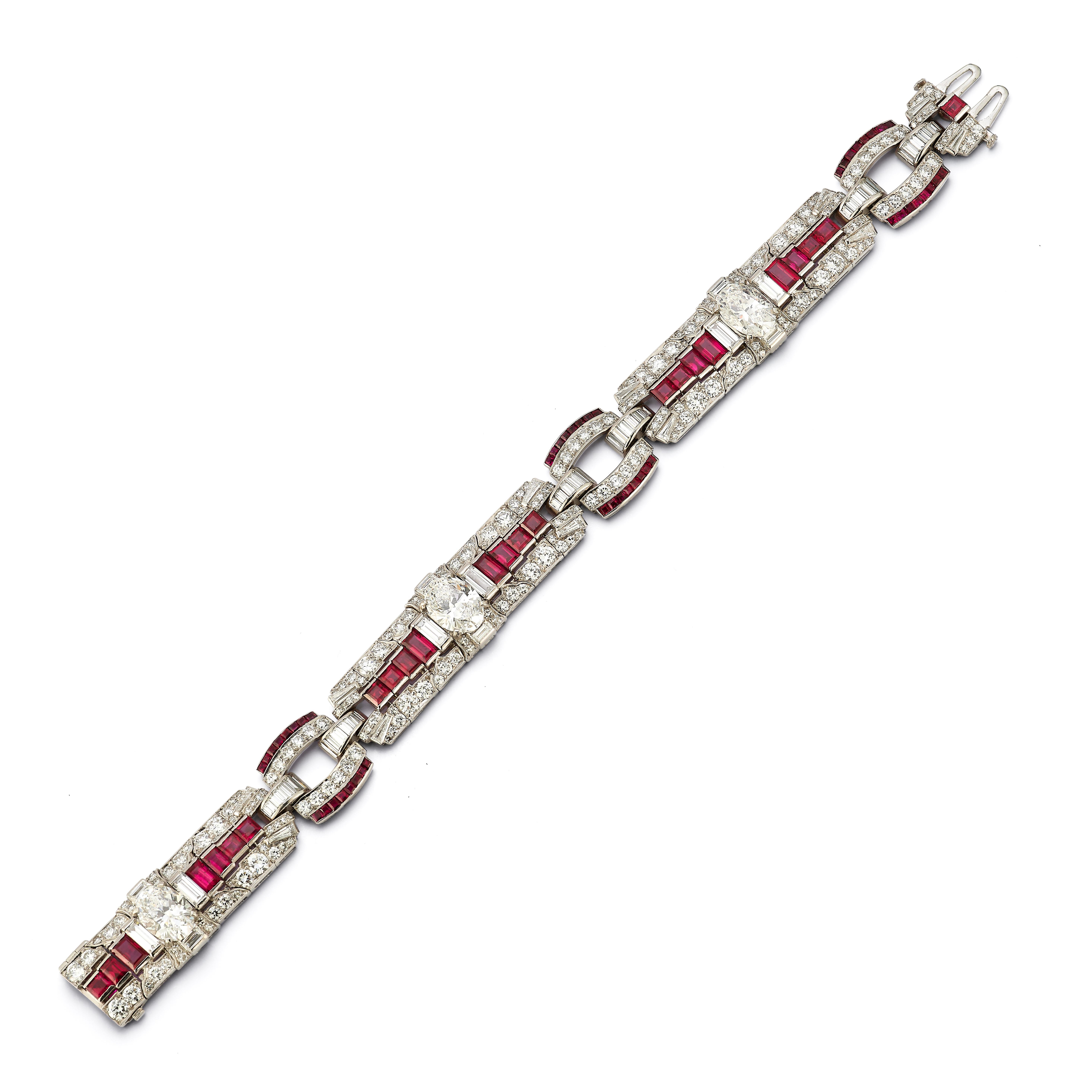 Raymond Yard Art Deco-Armband mit Rubin und Diamanten

Ein Platinarmband, besetzt mit 3 ovalen Diamanten mit einem Gewicht von ca. 1,85, 1,75 und 1,60 Karat, Diamanten im Rund- und Baguetteschliff sowie Rubinen im Rechteck-, Quadrat- und