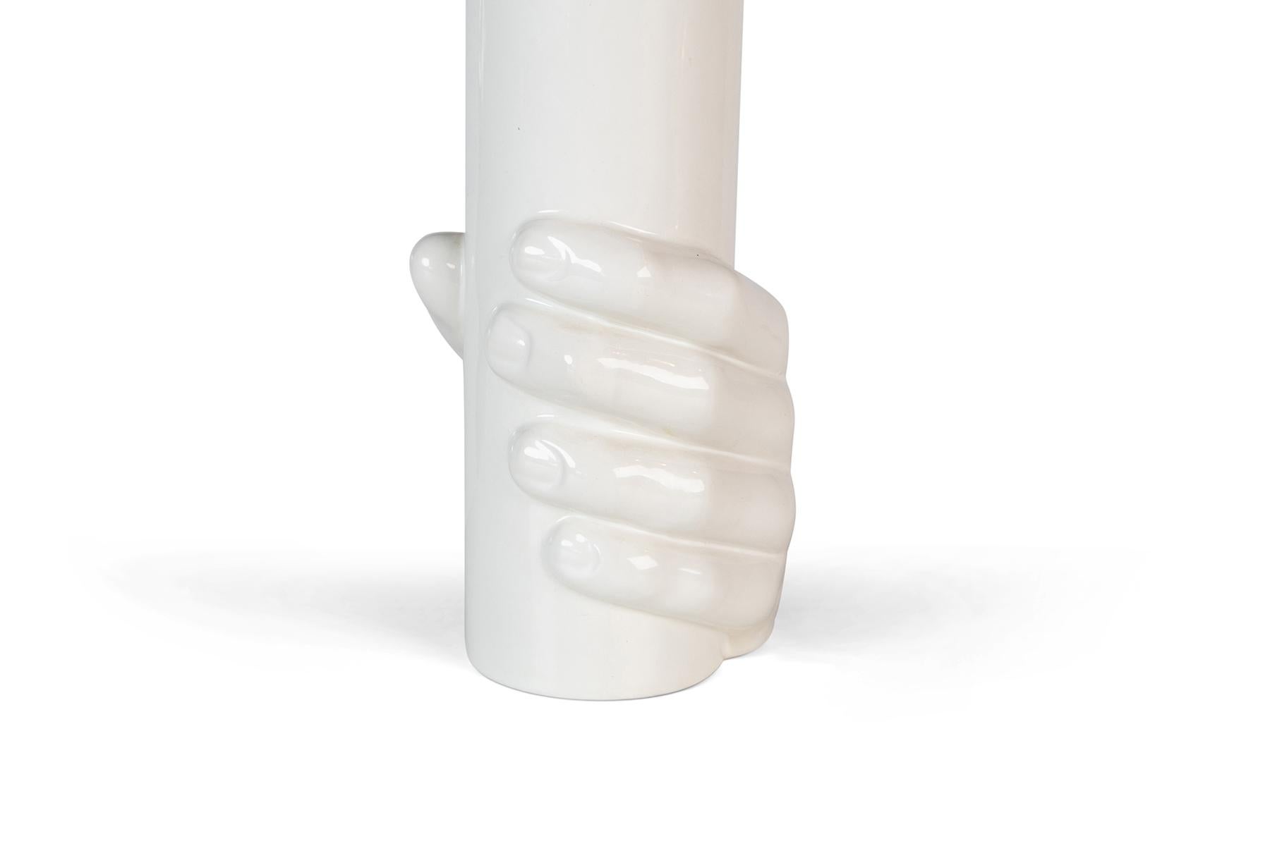 White cylindrical vase with a sculpted hand grasping the form by Raymor.