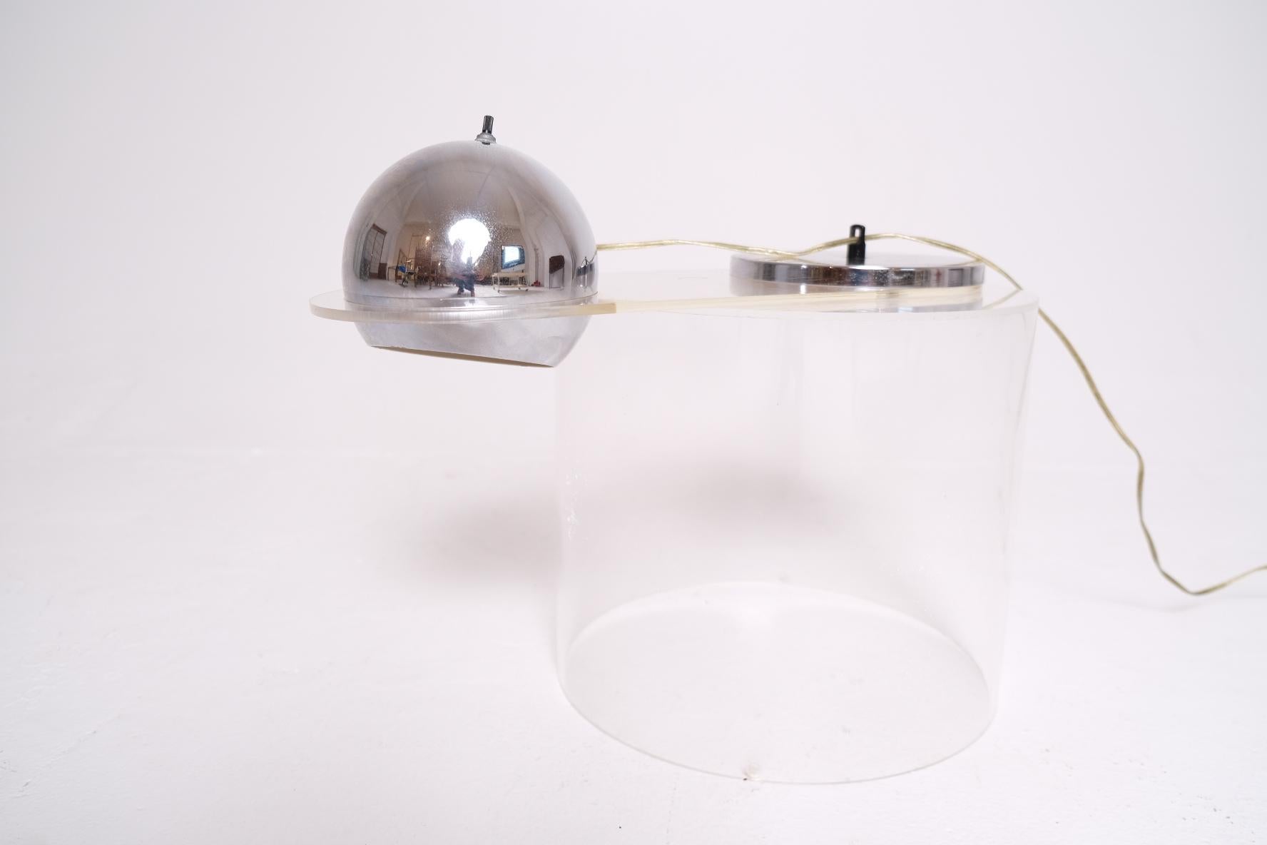 Designed in the late 1960s, the No. 7 piano lamp by Raymor exemplifies mid-century innovation in both form and function. It features a polished chrome hemispheric shade suspended on a curved Lucite arm, counterbalanced by a weighted chrome disc. The