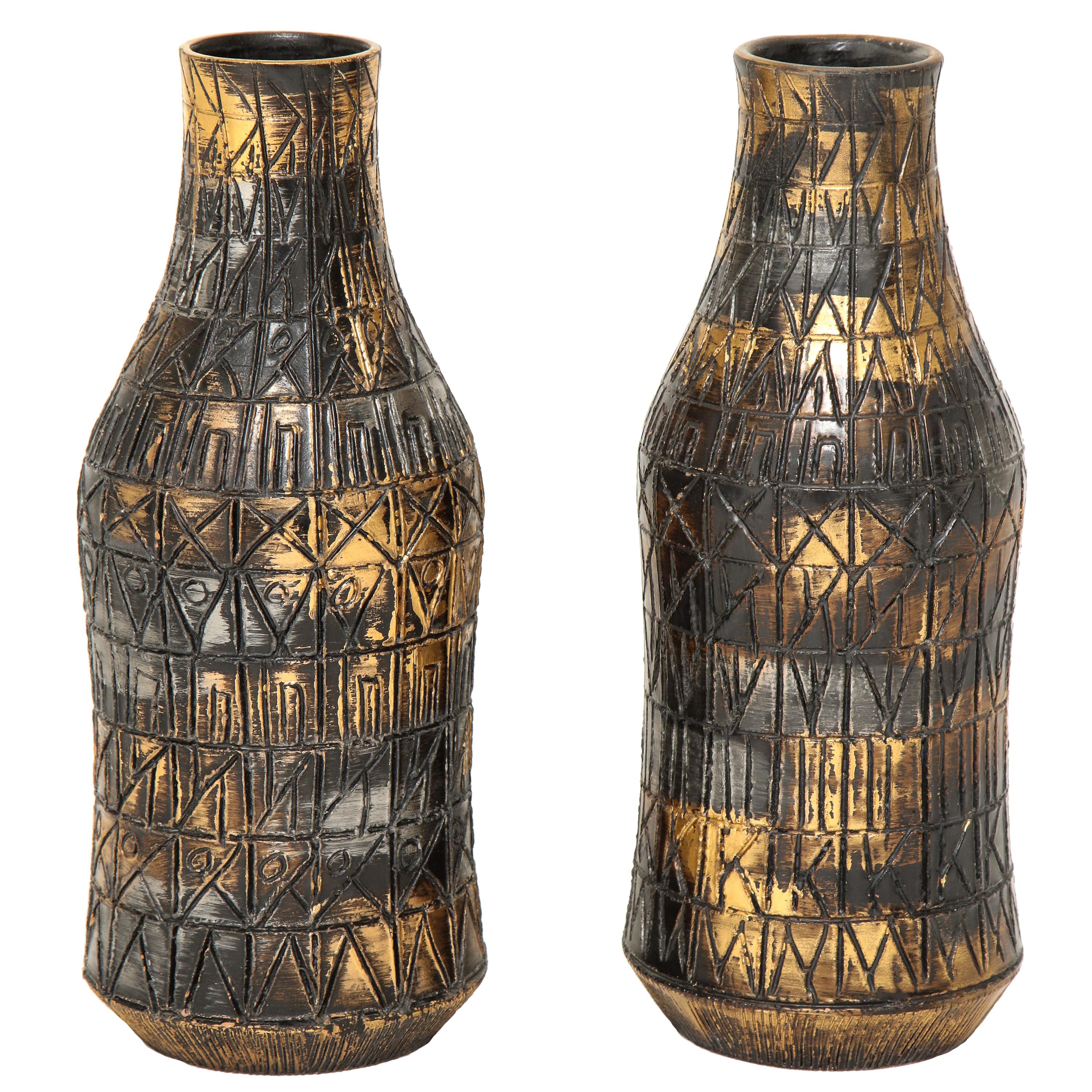 Raymor vases, ceramic, sgraffito, gold, silver, gunmetal, signed. A pair of medium scale bottle form vases with incised geometric patterns and glazed in a burnished gold, dark silver pewter with gunmetal bronze highlights. Signed Raymor 112 Italy on