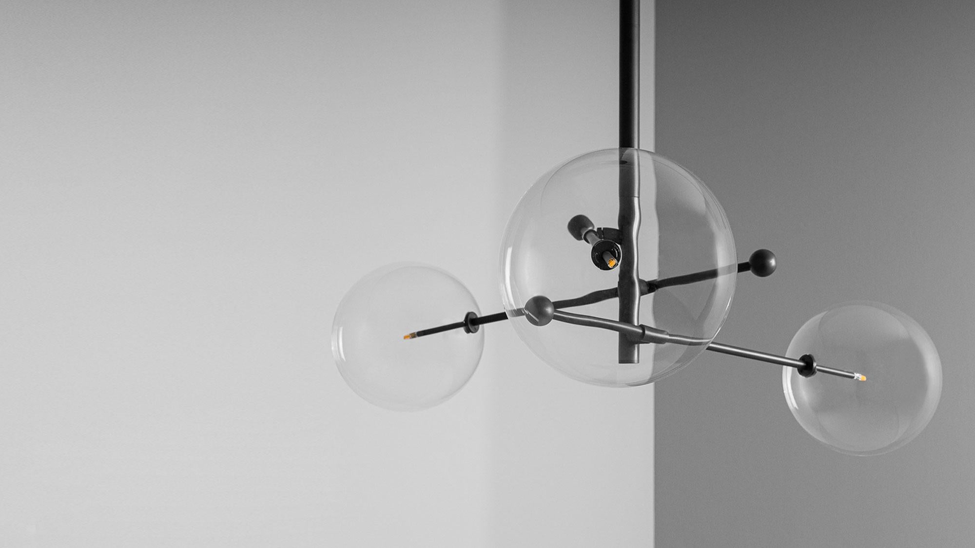 A trio of mouth-blown glass globes orbit a central axis, poised on adjustable cantilevered brass arms. The modular asymmetry of the intersecting angles forms a gyroscopic composition, bringing an interstellar elegance to a space.

Available in our