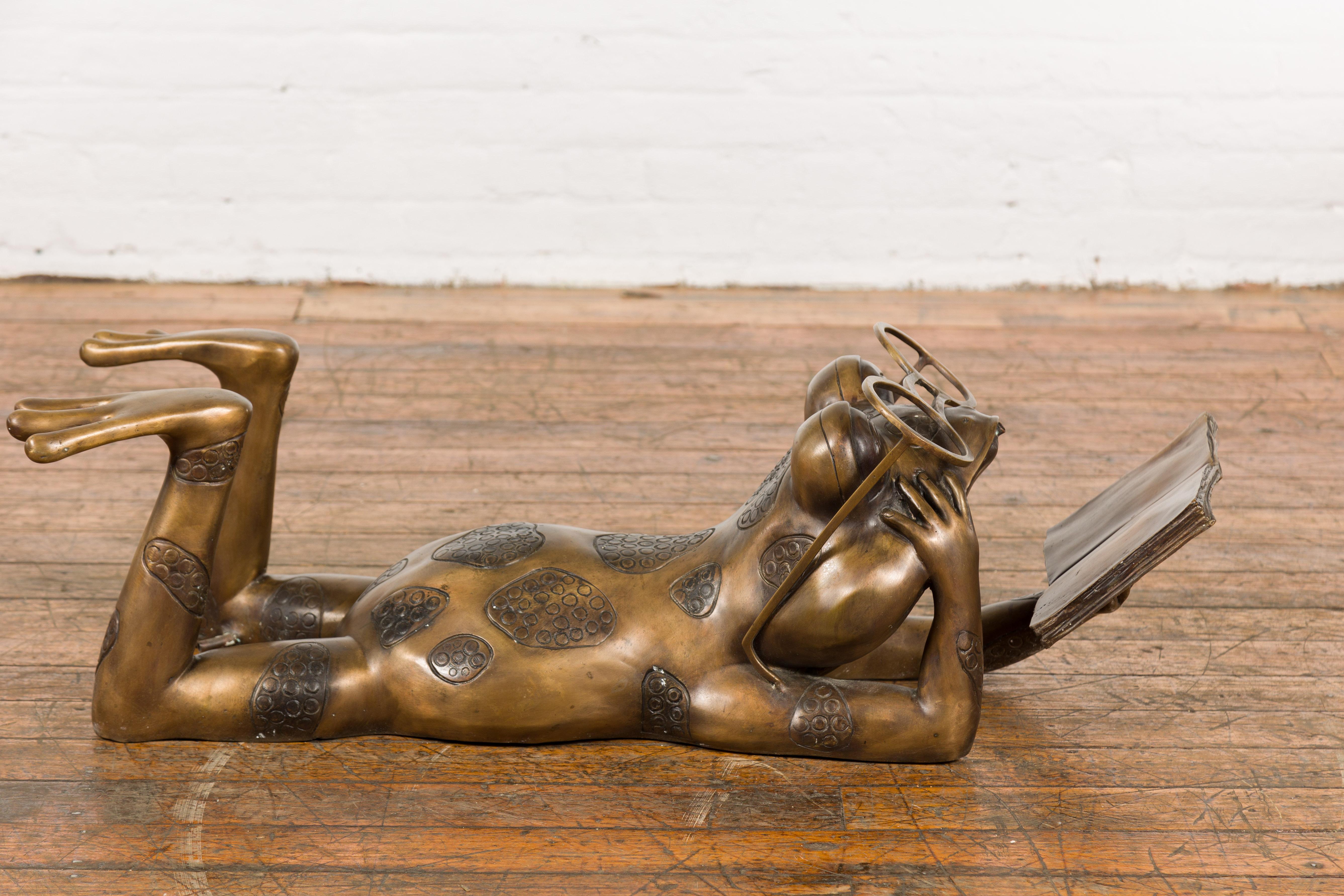 Wachsausschmelzverfahren gegossene Bronzeskulptur eines lesenden Frosches mit Brille in goldener Patina. Diese Skulptur aus Bronze mit Wachsausschmelzverfahren mit dem Titel 