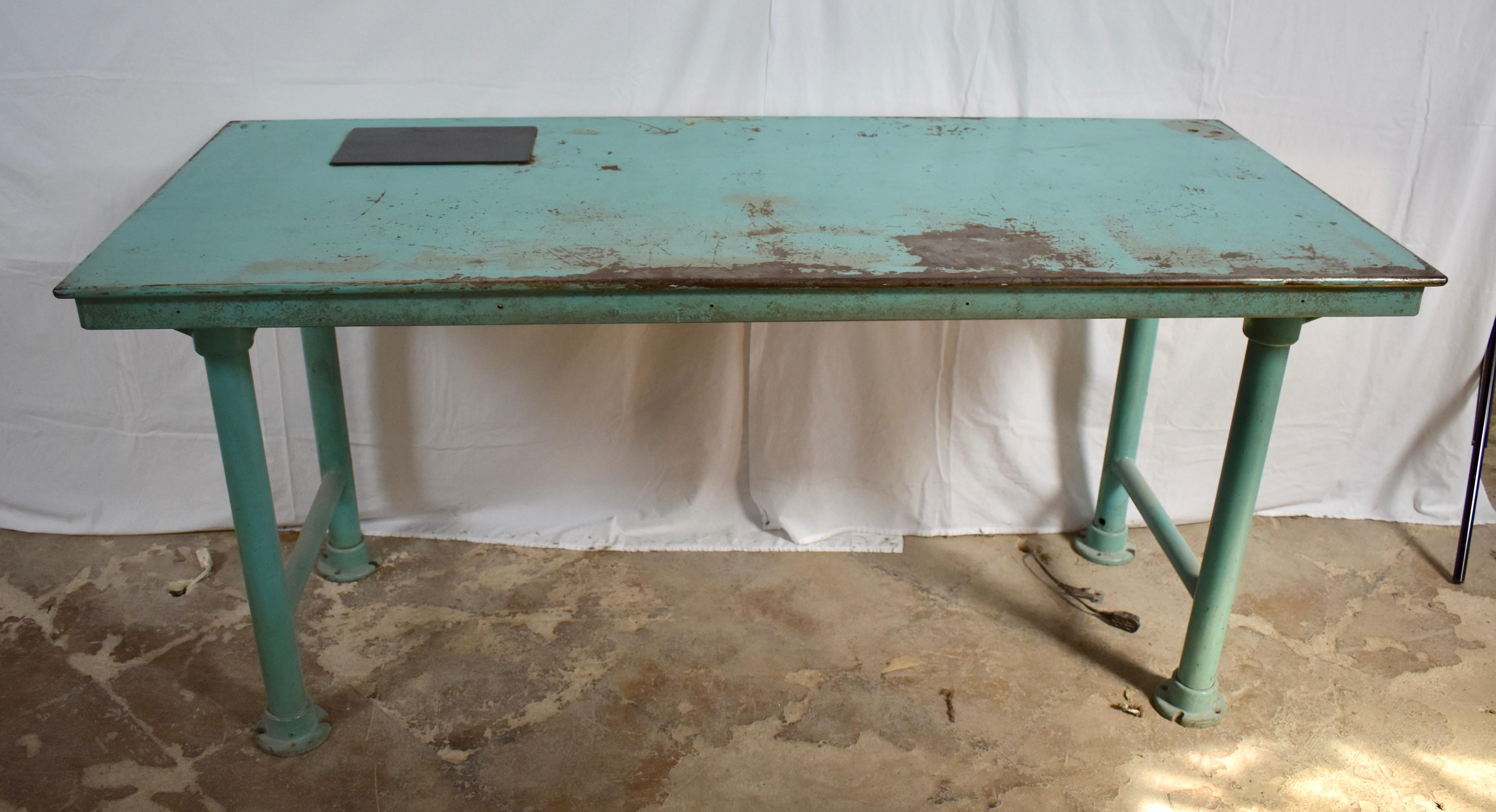 These reading textile machine works tables stand on pipe legs resting on cast feet and reinforced with cast gussets. The tops are rolled sheet steel. Each has a smoked plexiglass panel covering 8