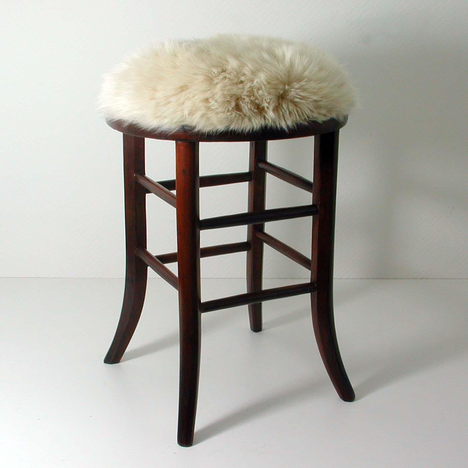 This 20th century stool was manufactured in Austria in the 1940s. The stool has got a walnut base and a cream colored real Iceland lamb fur seat. 

It has been completely restored: the wooden legs abraded and re-lacquered, the seat upholstered