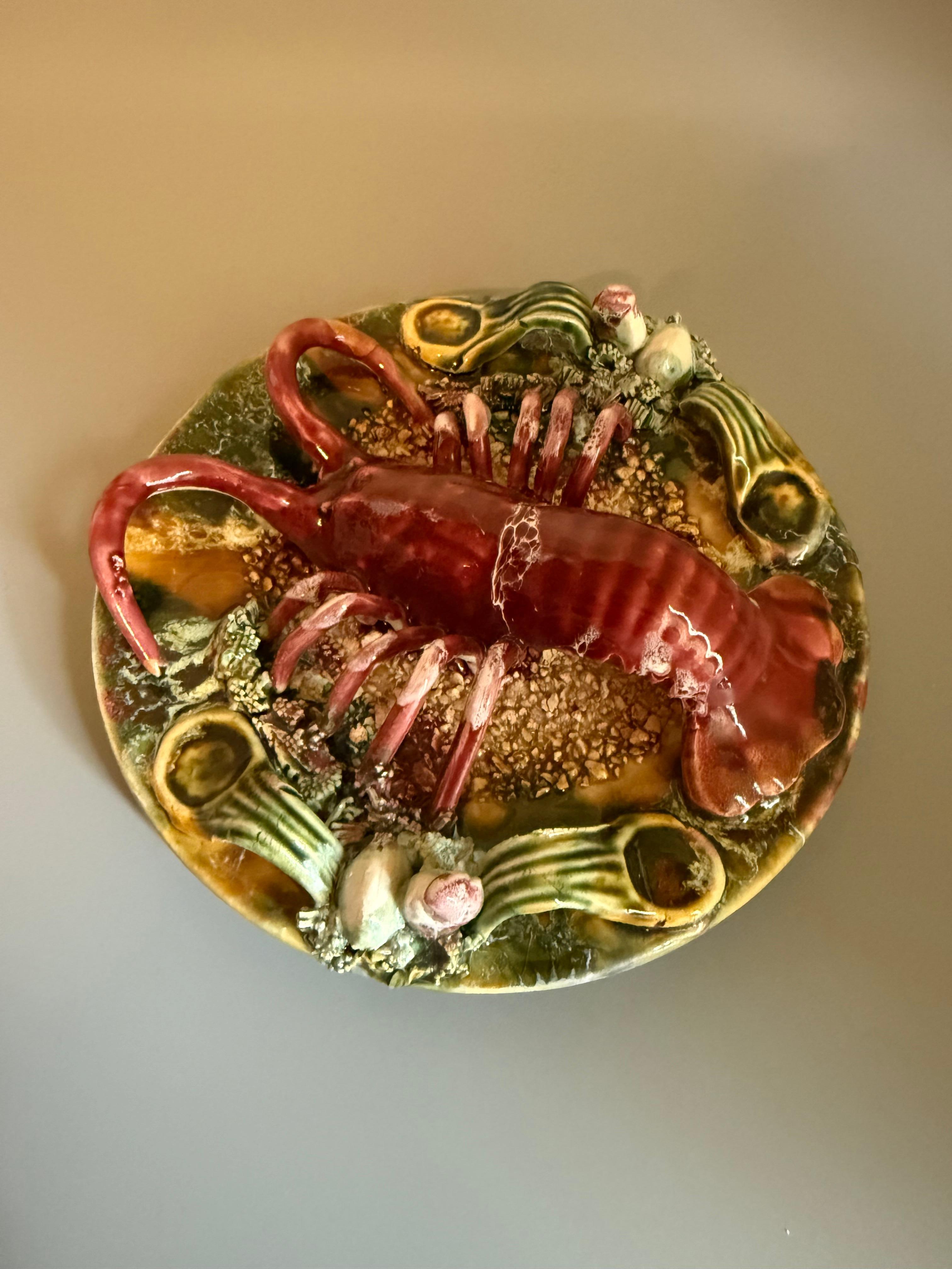 Palissy ware is a ceramic technique, named after the French potter Bernard Palissy, known for its realistic, high-relief depictions of nature, often including animals, plants, and insects. 
This particular plate showcases a deeply molded bas-relief