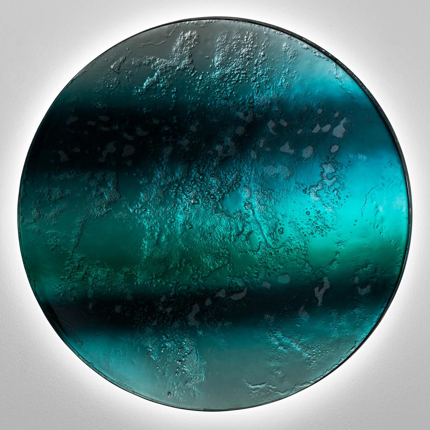 Wanddekoration Realto Round aus 2 Schichten gebranntem Glas mit
unregelmäßige Ränder mit Farbverläufen von dunklem Dunkelgrün zu hellerem Grün 
intensiv grün mit versilberter Rückseite in mittelalterlichem Finish. Mit
Holzrahmen auf der Rückseite in