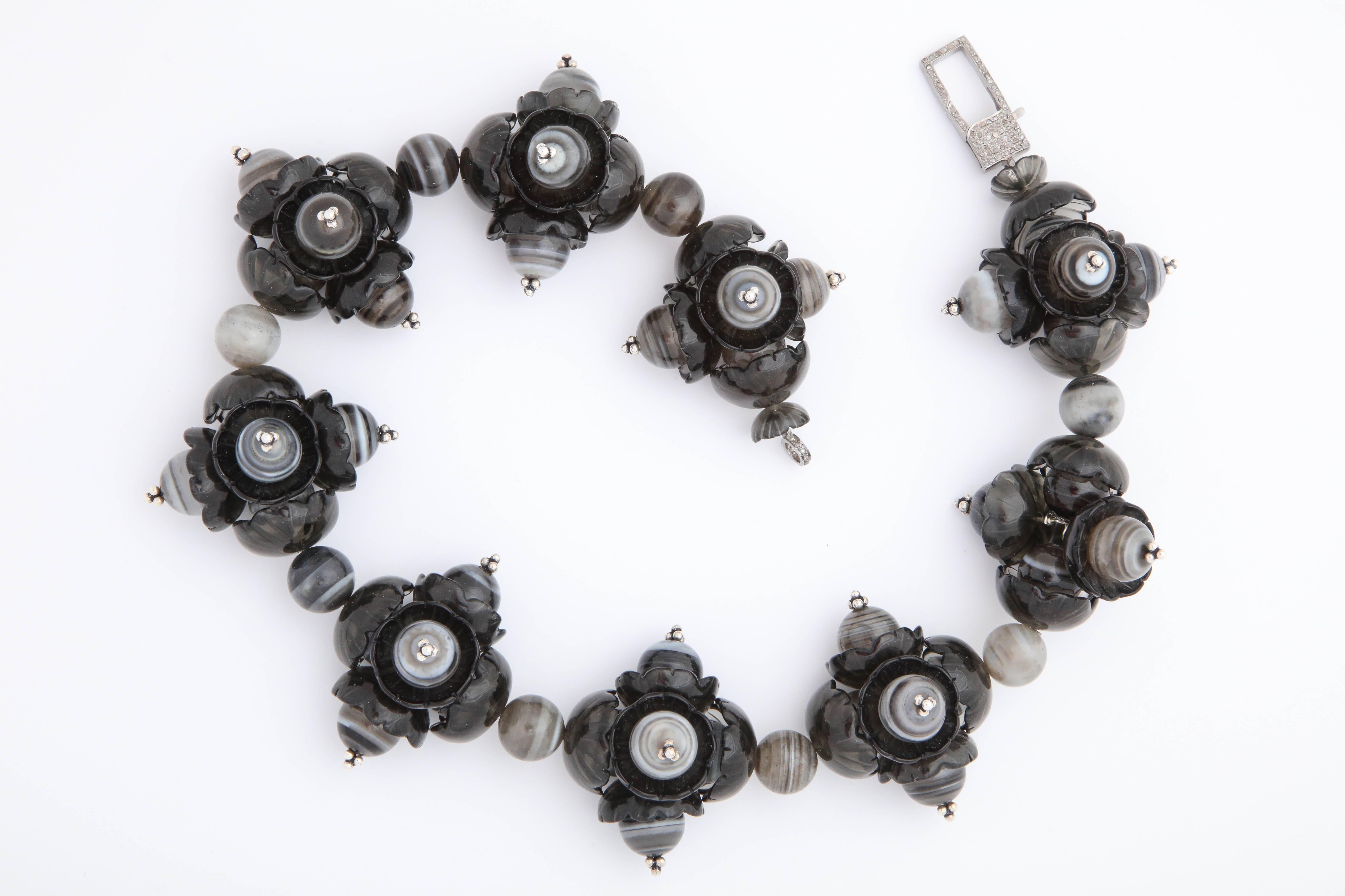A wreath necklace composed of smokey quartz flowers, banded agate beads and rhodium plated sterling silver flower headpins. There is a rhodium plated sterling silver and diamond clasp.
Length: 18.50 inches