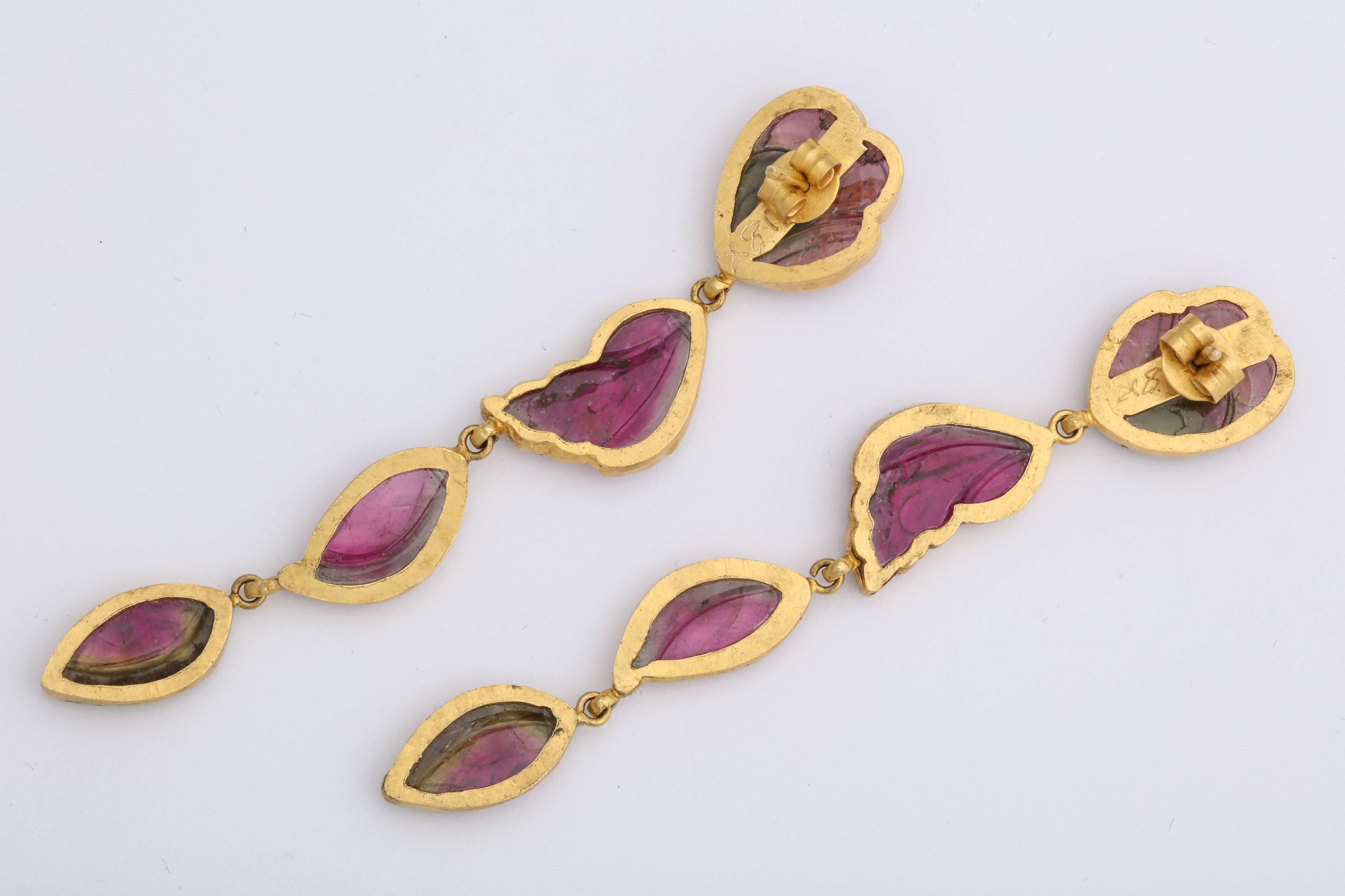 A pair of carved watermelon tourmaline pendant earrings. There are three carved leaf tourmaline plaques per earring, each suspended from a tourmaline flower plaque stud. The tourmaline plaques have been bezel set in 18kt yellow gold.  

Length: 3.12