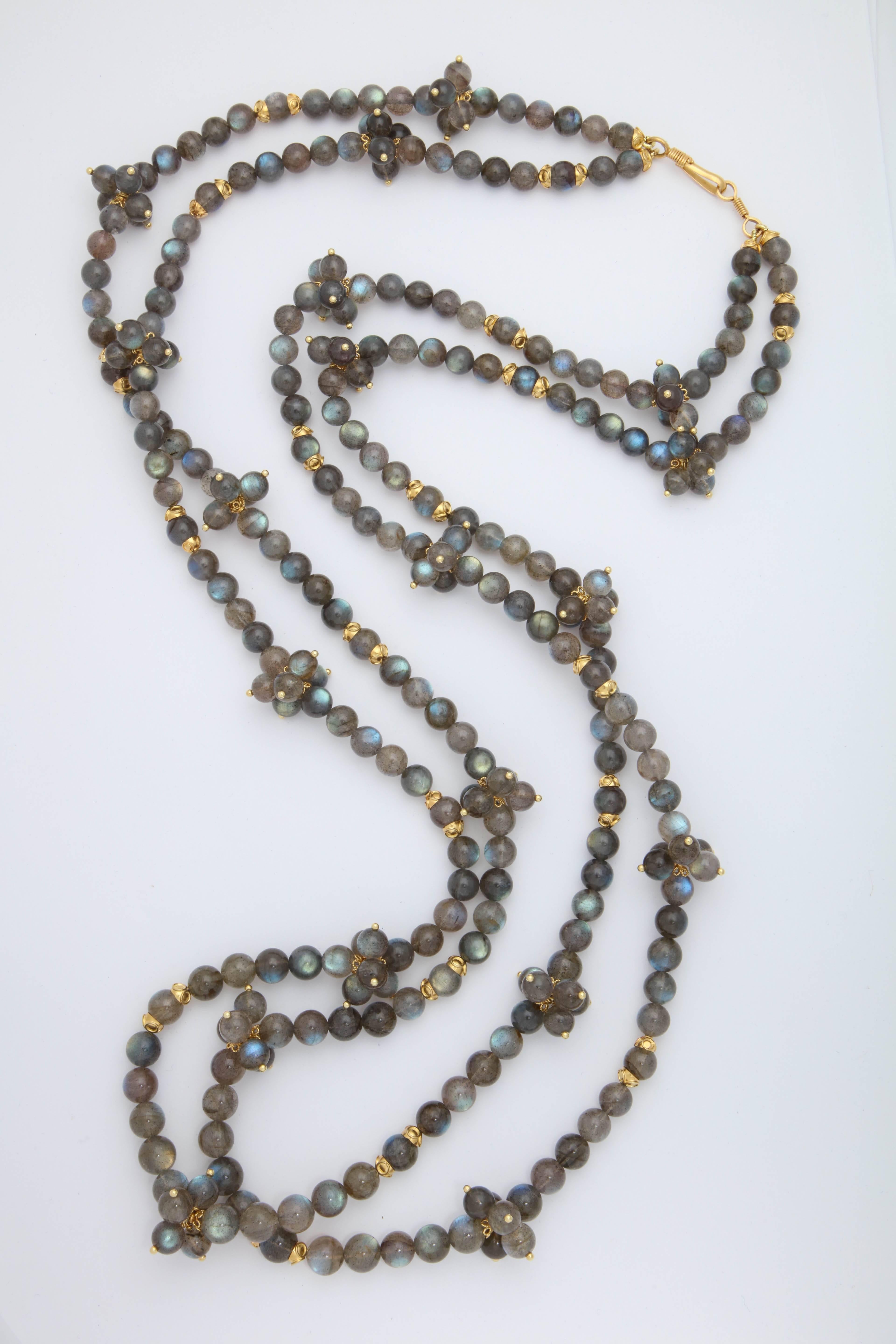 A two strand nestled necklace composed of round polished labradorite beads, 18kt yellow gold caps and headpins. The necklace has sections of labradorite beads separated by clusters of labradorite beads and gold caps.
Length: 44.00 inches
