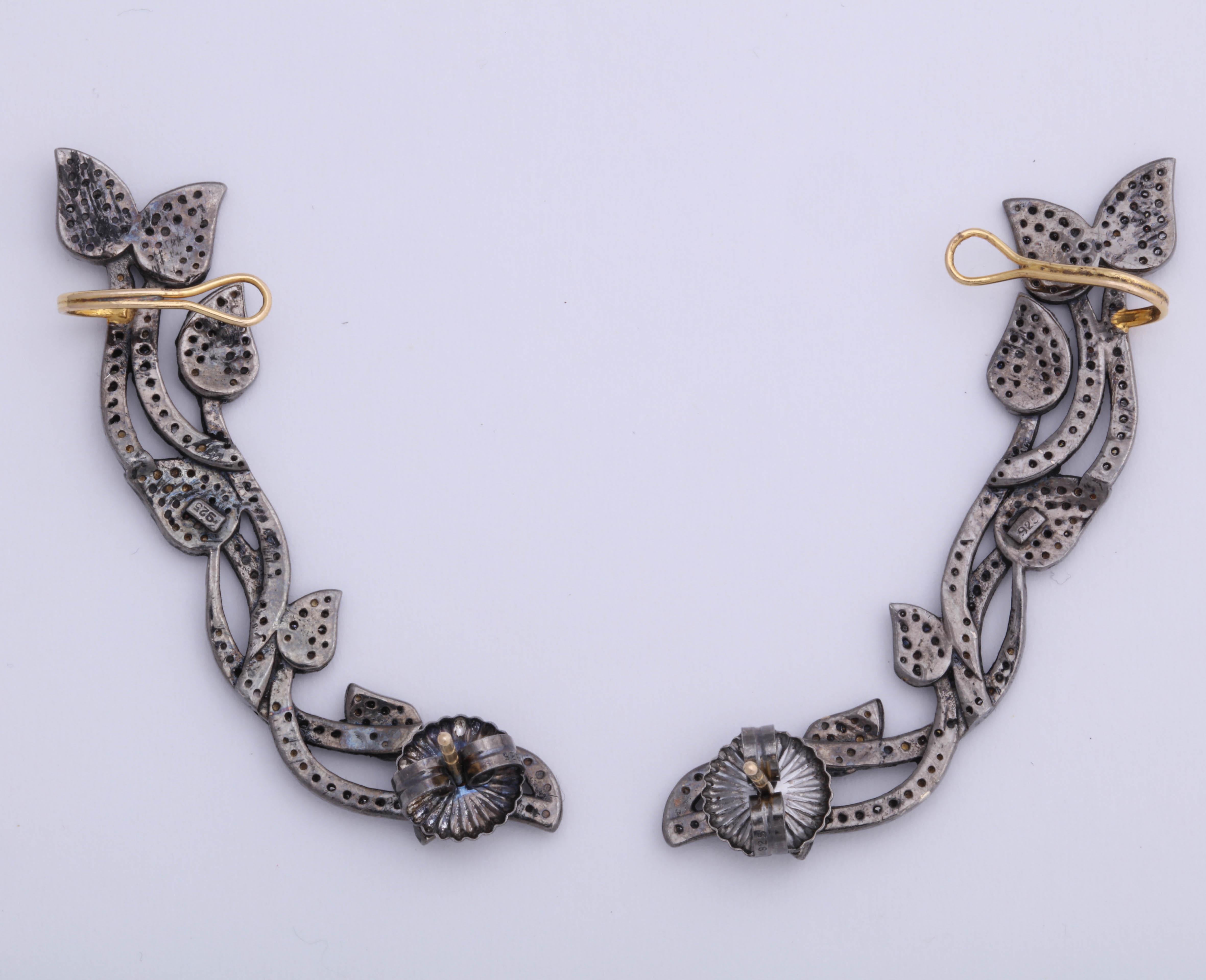 A pair of sterling silver and diamond vine ear cuffs. There are approximately 1.25cts of diamonds.
The posts and ear hook are 14kt yellow gold.

Length : 2.00 inches