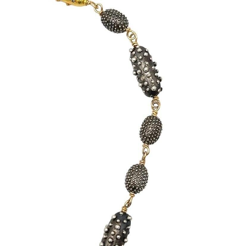 A silver, 18 karat yellow gold and colored diamond necklace, Rebecca Koven.  Designed as a length of oblong oxidized silver beads connected by gold wire, the beads with applied beadwork in silver, with two (2) oblong gold beads studded with numerous