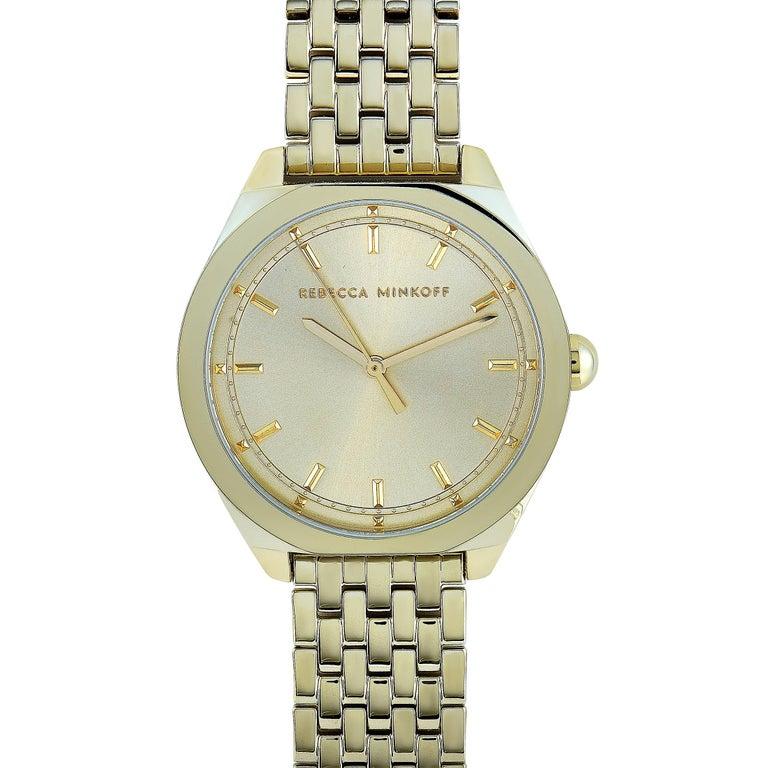 This is the Rebecca Minkoff Amari, reference number 2200326. The watch is presented with a yellow gold ion-plated stainless steel case that measures 38 mm in diameter. The case is water-resistant to 30 meters and mounted onto a matching gold-tone