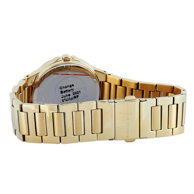 This is the Rebecca Minkoff Cali watch, reference number 2200304. It is presented with a gold ion-plated stainless steel case that is mounted onto a matching gold-tone stainless steel bracelet. The case measures 34 mm in diameter and is