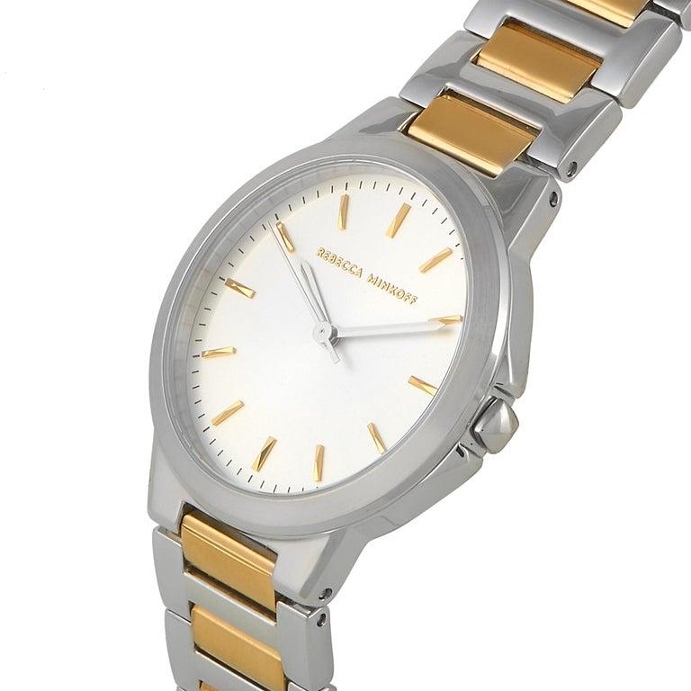 This is the Rebecca Minkoff Cali watch, reference number 2200323. It is presented with a stainless steel case that is mounted onto a two-tone stainless steel bracelet. The case measures 34 mm in diameter and is water-resistant to 30 meters. The