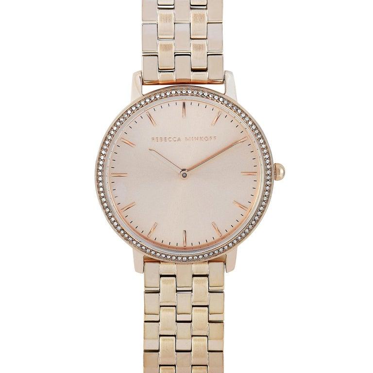 This is the Rebecca Minkoff Major, reference number 2200349. The watch boasts a 35 mm carnation gold-tone stainless steel case that is embellished with crystals. The case is water-resistant to 30 meters and mounted onto a carnation gold-tone