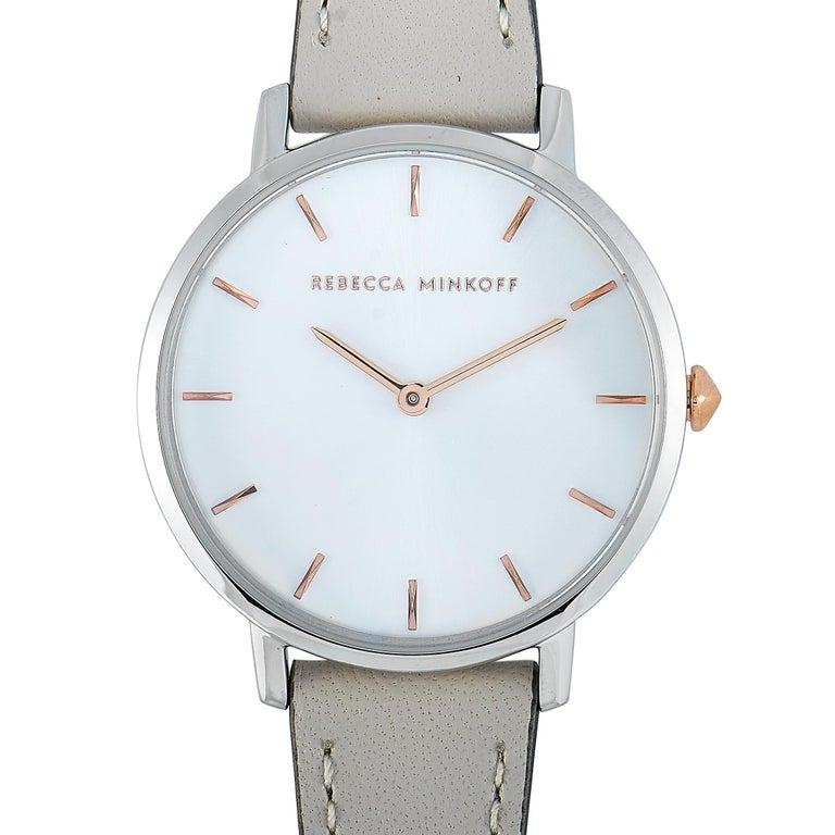 This is the Rebecca Minkoff Major watch, reference number 2200238. It boasts a 35 mm silver-tone stainless steel case that is water-resistant to 30 meters. The case is presented on a light gray leather strap fitted with a tang buckle. This model is