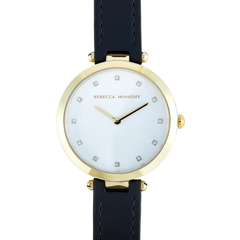 This is the Rebecca Minkoff Nina watch, reference number 2200401. It boasts a 33 mm gold ion-plated stainless steel case that is water-resistant to 30 meters. The case is presented on a black leather strap fitted with a tang buckle. This model is