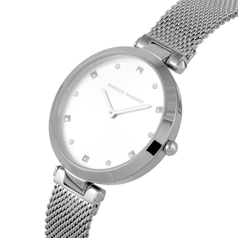 This is the Rebecca Minkoff Nina watch, reference number 2200299. It is presented with a silver-tone stainless steel case that is mounted onto a matching silver-tone stainless steel mesh bracelet. The case measures 33 mm in diameter and is