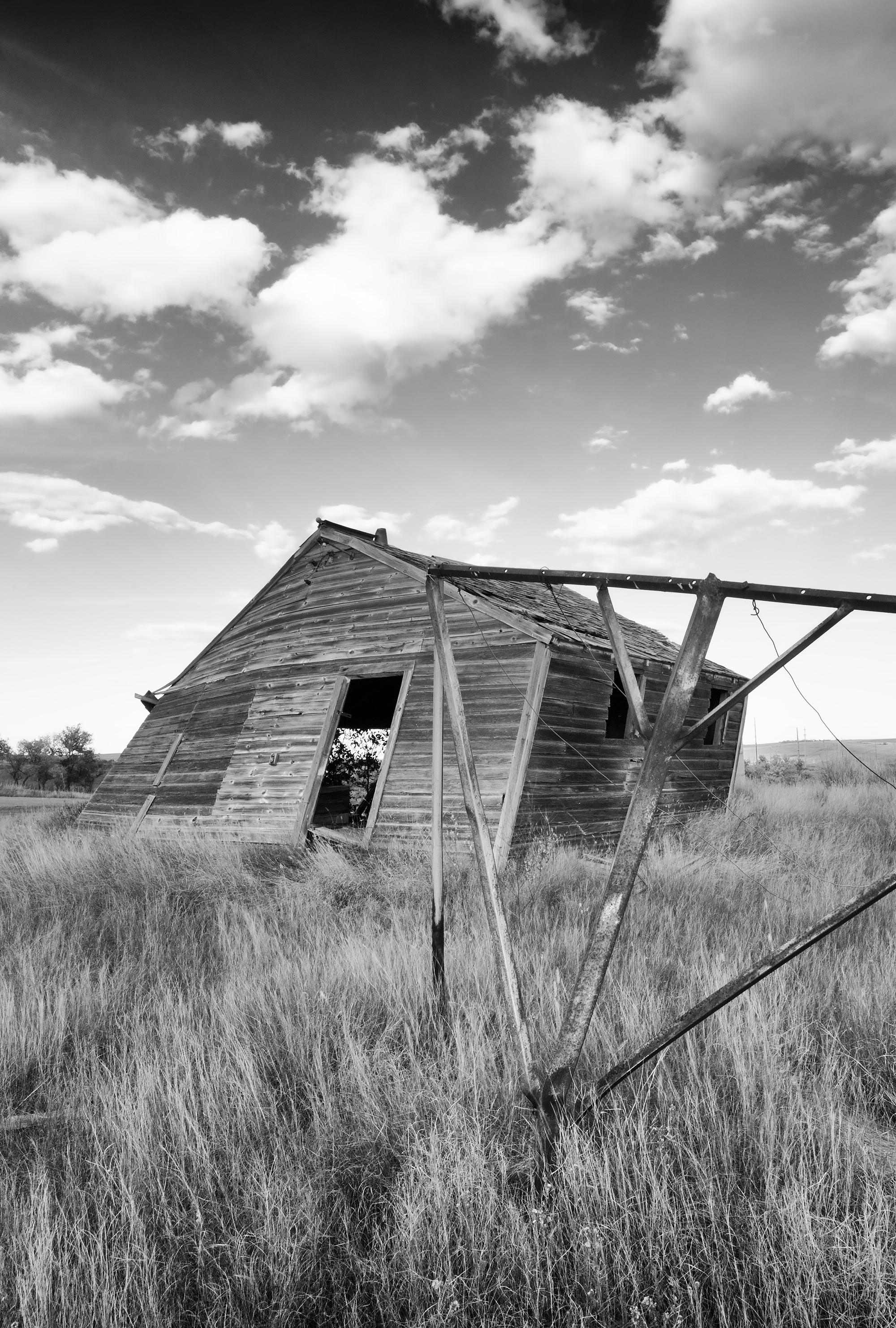 Rebecca Skinner’s “Alkabo II” is a 24 x 36 inch black and white photograph captured in a North Dakota ghost town. Dramatic sky frames a weathered structure in this beautiful contemporary landscape. The frameless metal print has a satin finish and is