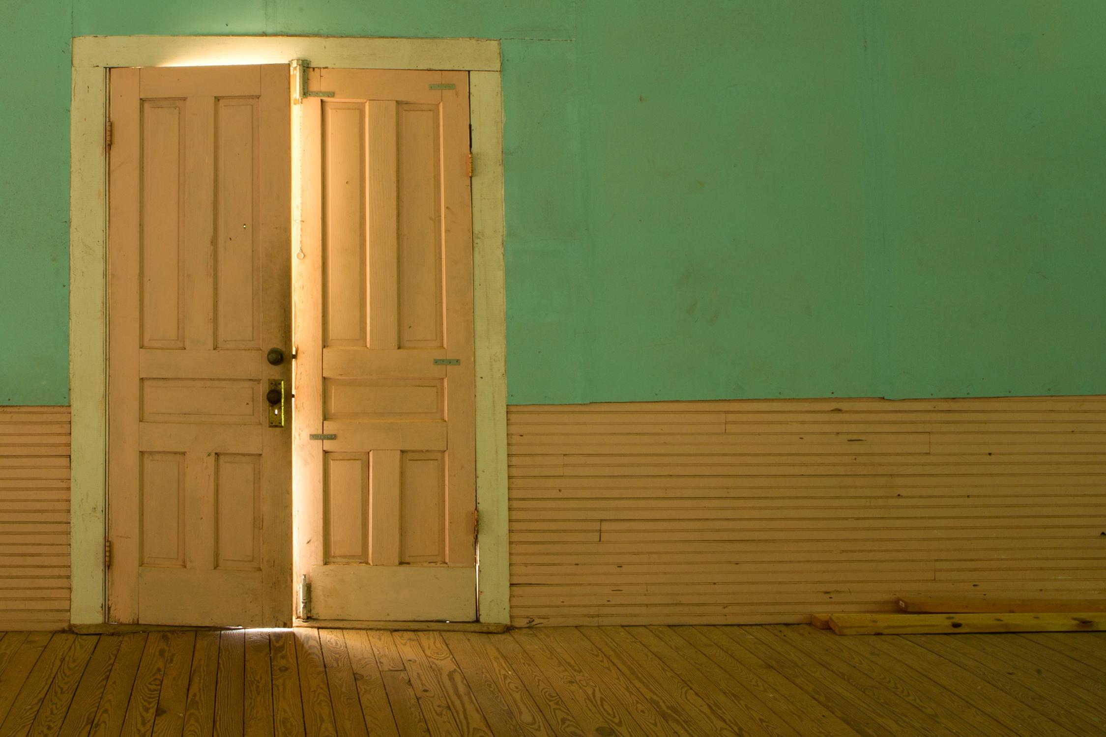 Rebecca Skinner’s “Anticipation” is a 12 x 18 inch color photograph of doors in the interior of an abandoned church found in rural Georgia. A door is slightly ajar offering a glimpse of light into the peach and green painted room. The frameless