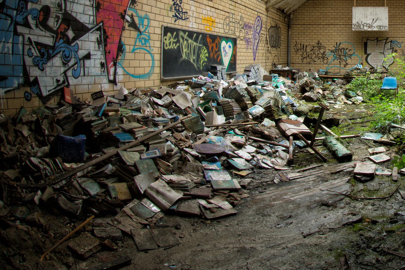 Rebecca Skinner’s “Book Beauty 6” is a 11 x 17 inch metal print of a gymnasium full of discarded books left to decay in a deserted school. The color photograph with hues of green and blue is an example of how quickly nature reclaims the abandoned.