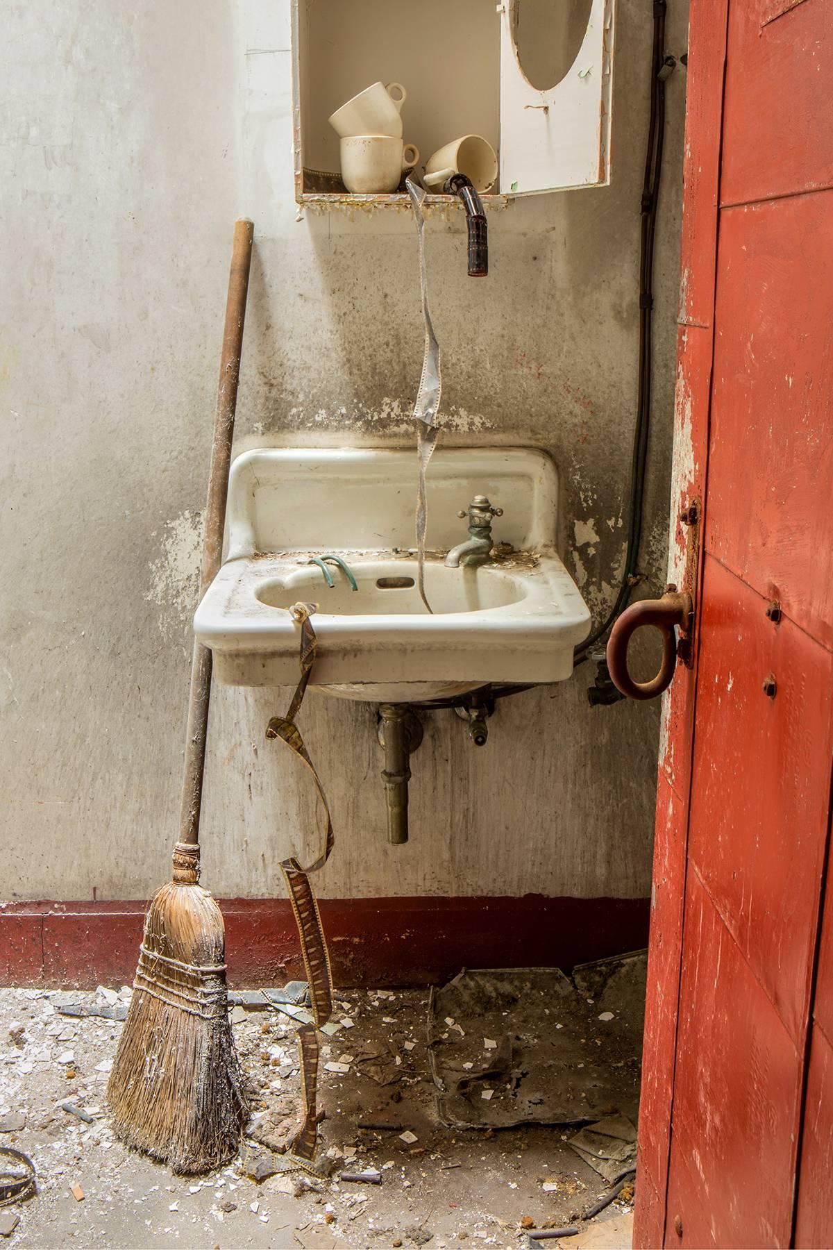 Rebecca Skinner Color Photograph - "Dirty Film", abandoned, theater, sink, broom, red, film, color photograph