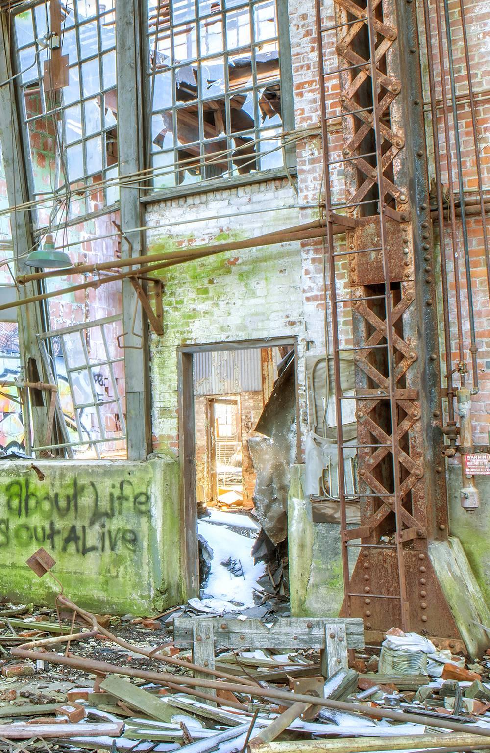 Rebecca Skinner’s “Endure” was photographed in an abandoned train repair yard. The 30 x 20 inch color photograph is of an industrial scene in a state of decay with cool tones of blue and green. The print has a satin finish and is infused directly