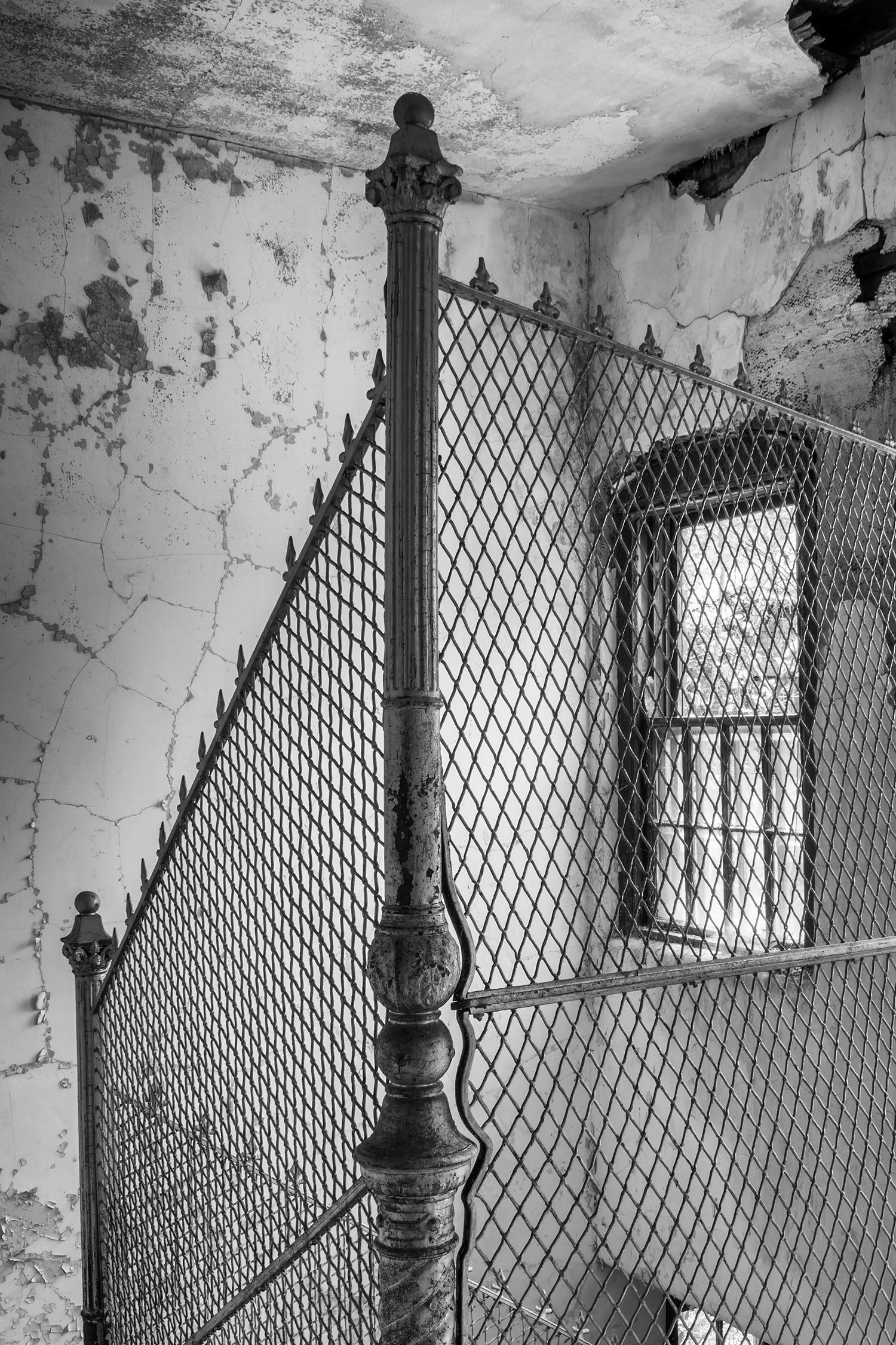 Rebecca Skinner’s “Escape” is a 24 x 16 inch black and white print of protective fencing around a stairwell at an abandoned hospital. With satin finish, the image is infused directly into metal making it waterproof and easy to clean. This frameless