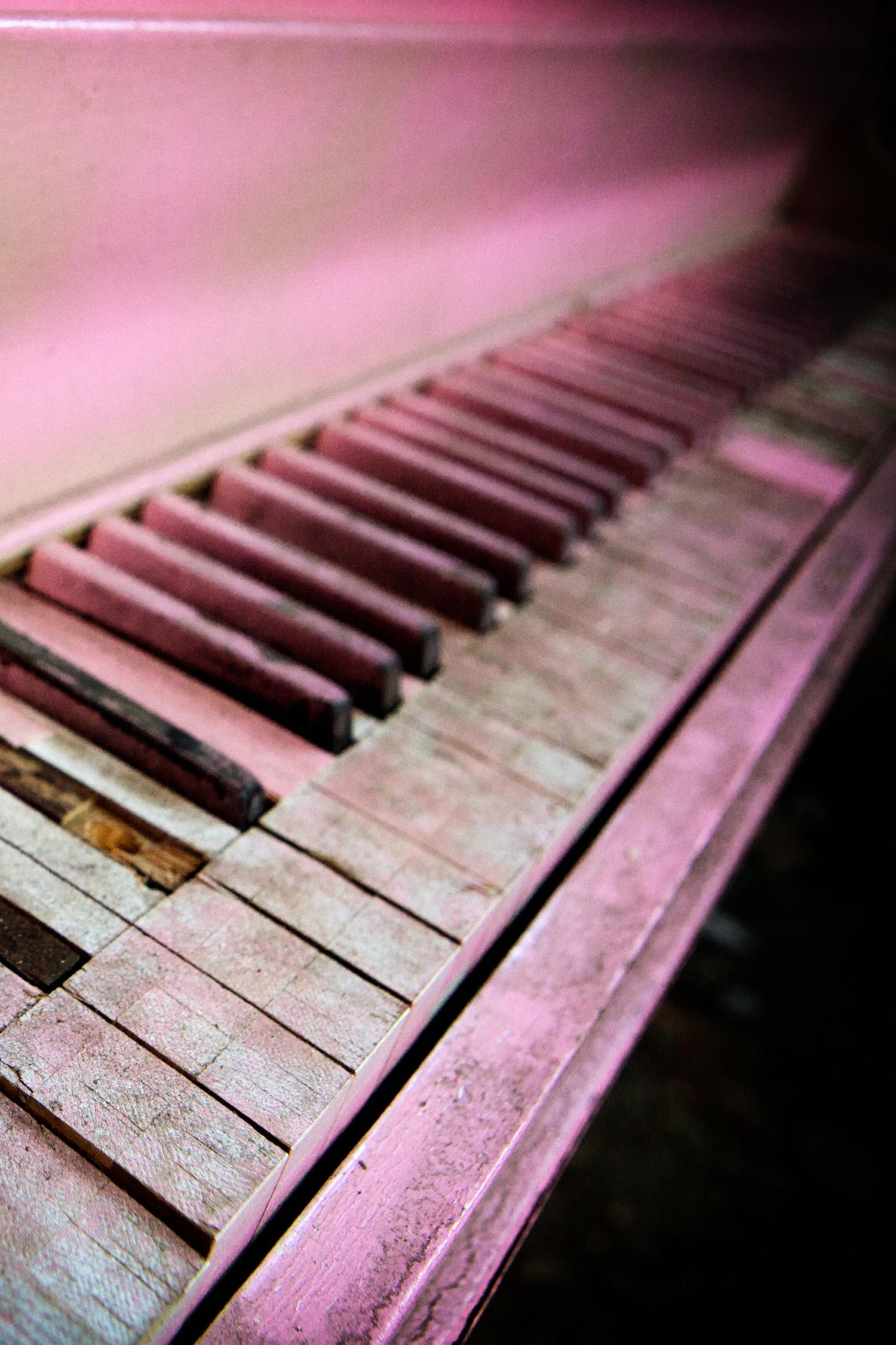 Rebecca Skinner’s “Pink Piano II” is a 16 x 24 inch contemporary metal print of the keys on an abandoned pink piano located in the remnants of an auditorium in Indiana. The focus softens at the edges adding a grittiness to the image giving it the