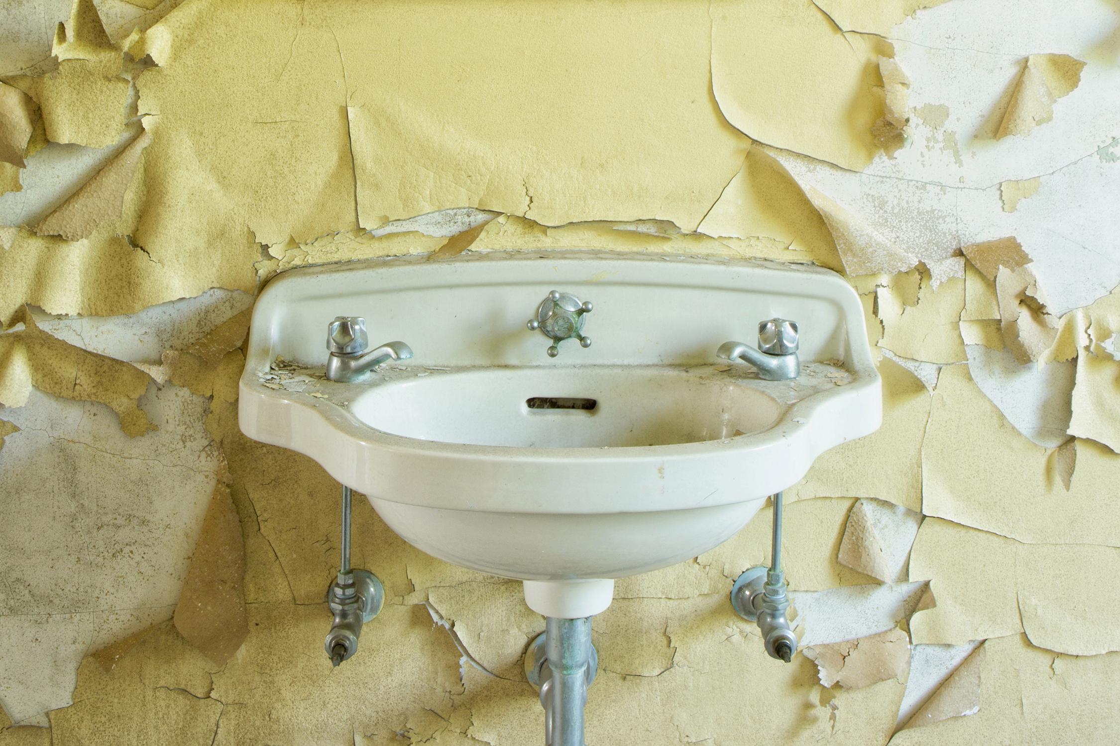 Rebecca Skinner’s “Sink VI” is an 8 x 12 inch metal print photographed at an abandoned hospital. The color photograph is of a vintage sink against a yellow wall with peeling paint. The frameless print has a clear matte finish and are infused