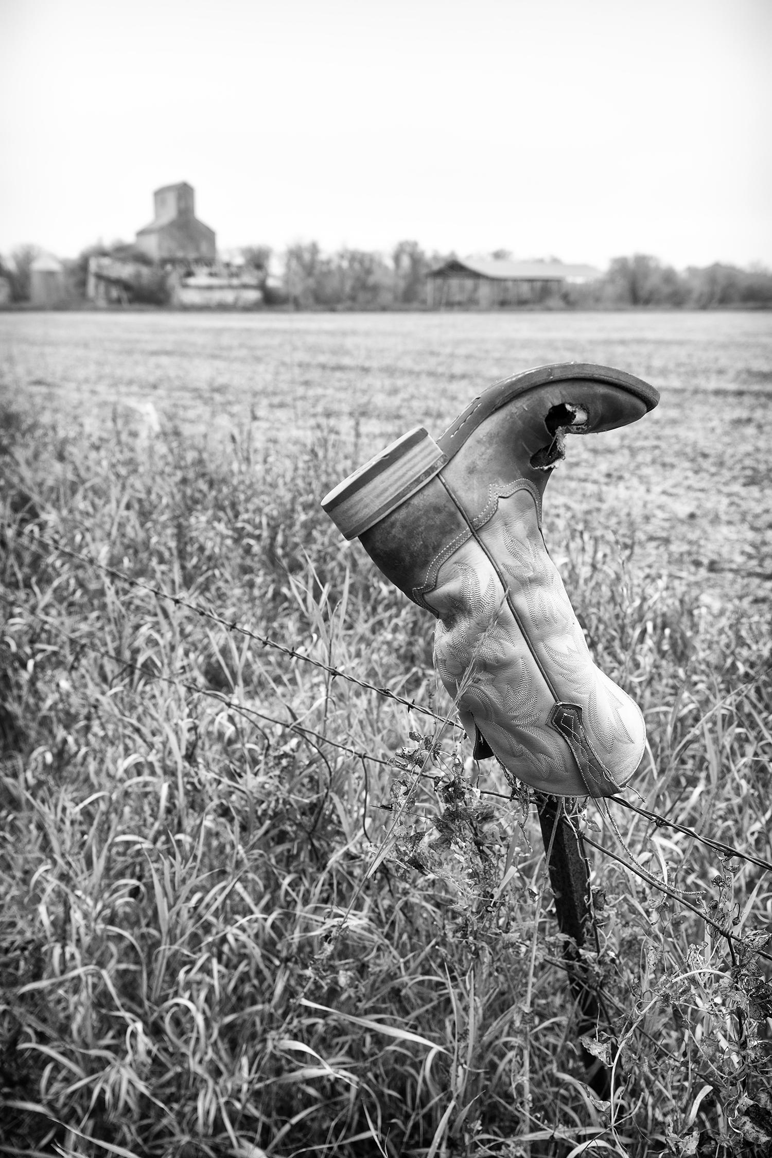 Rebecca Skinner Landscape Photograph – "Sorrow", zeitgenössisch, Landschaft, Stiefel, Zaun, Cowboy, North Dakota, Fotografie