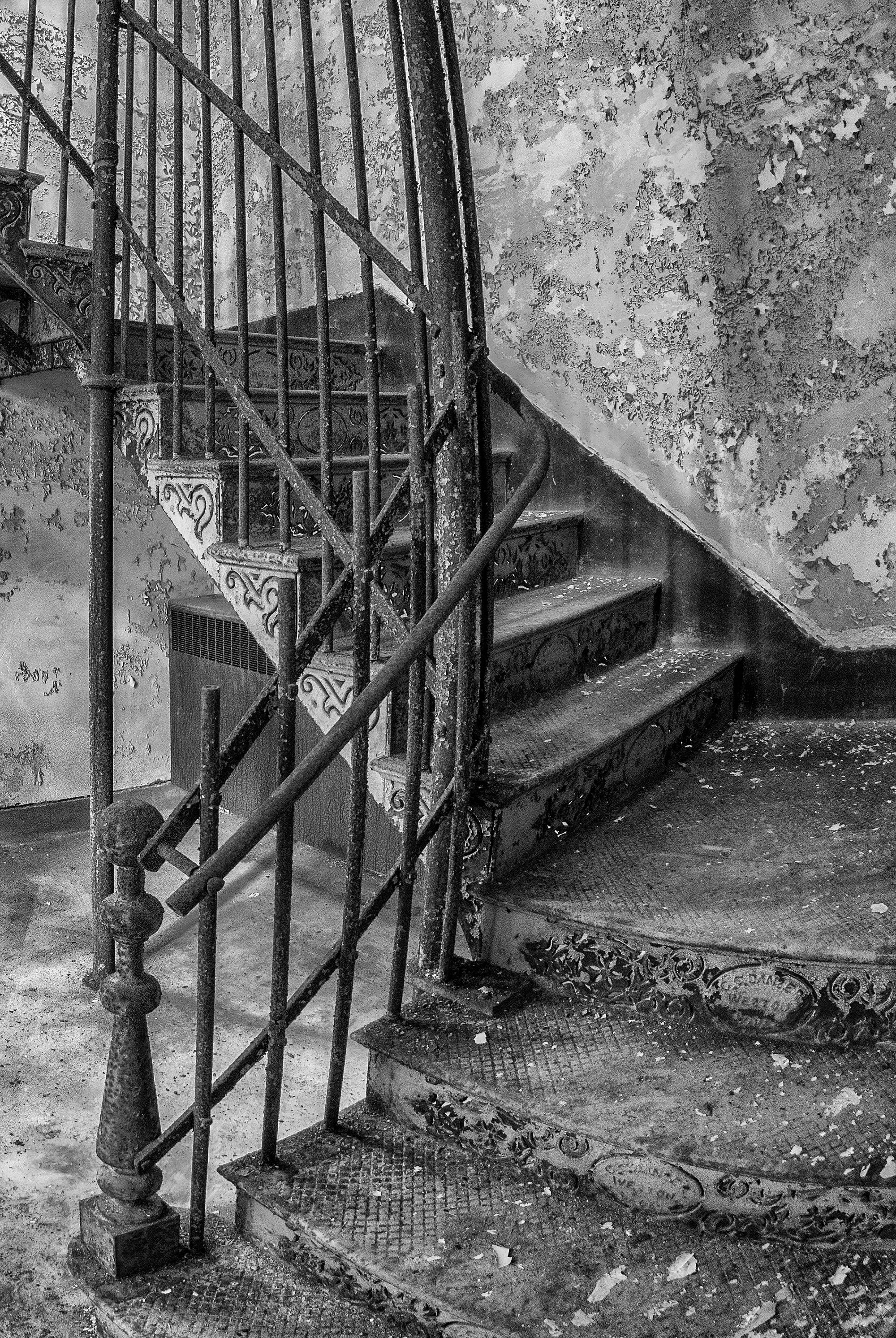 Rebecca Skinner’s “Stairway” was photographed at an abandoned asylum and is part of her “Forgotten” series raising mental health awareness. A fisheye lens gives the ornate, iron staircase a never ending feeling. Patterned cutouts in the steel risers