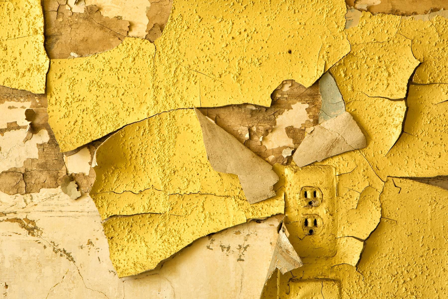 "Waning", abandoned, peeling paint, electrical, outlet, yellow, color photograph - Photograph by Rebecca Skinner