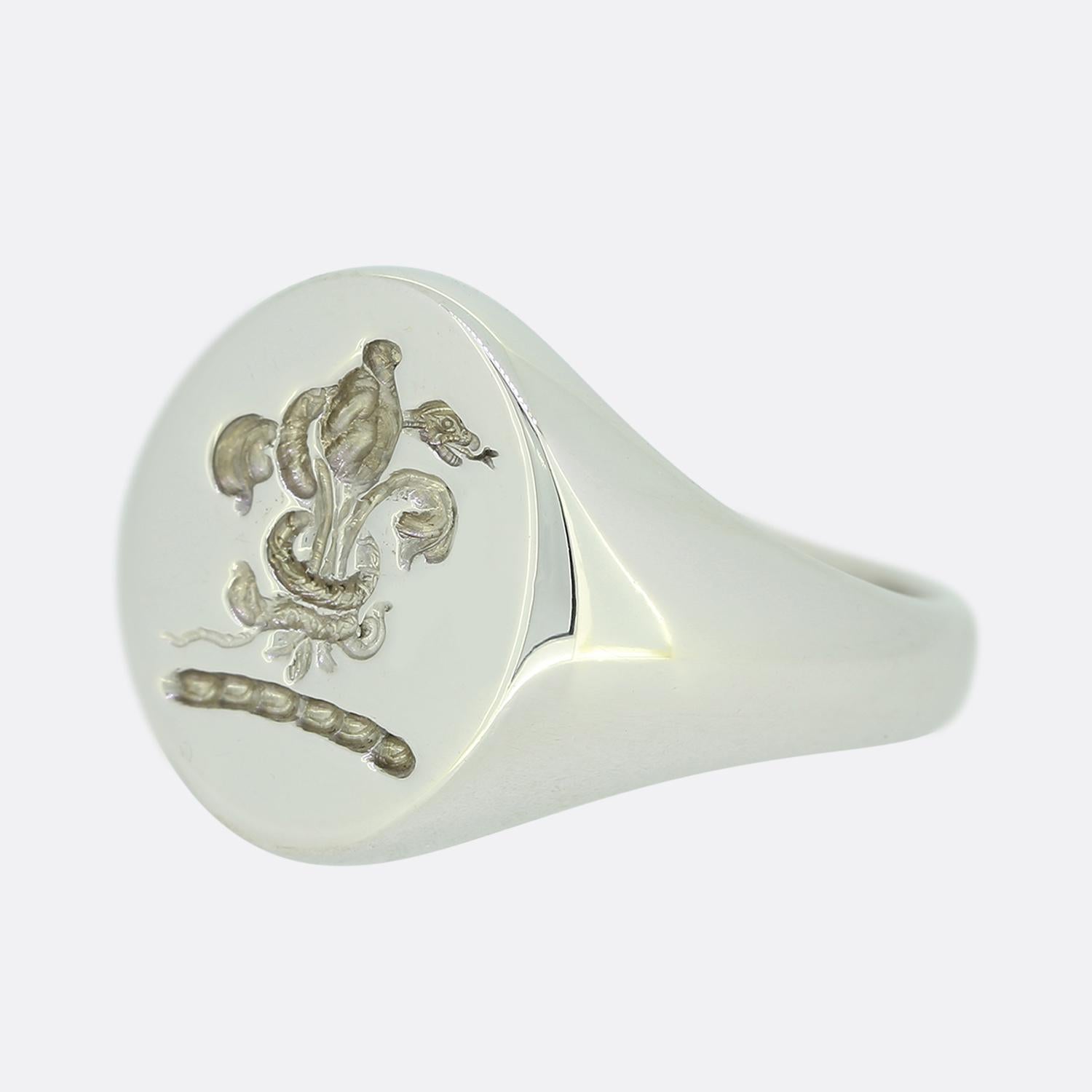 This is a modern 18ct white gold oval signet ring. The ring has an intaglio on the front of the head depicting a fleur de lis style design. The ring was made by London based company Rebus who specialise in crafting exceptional quality signet