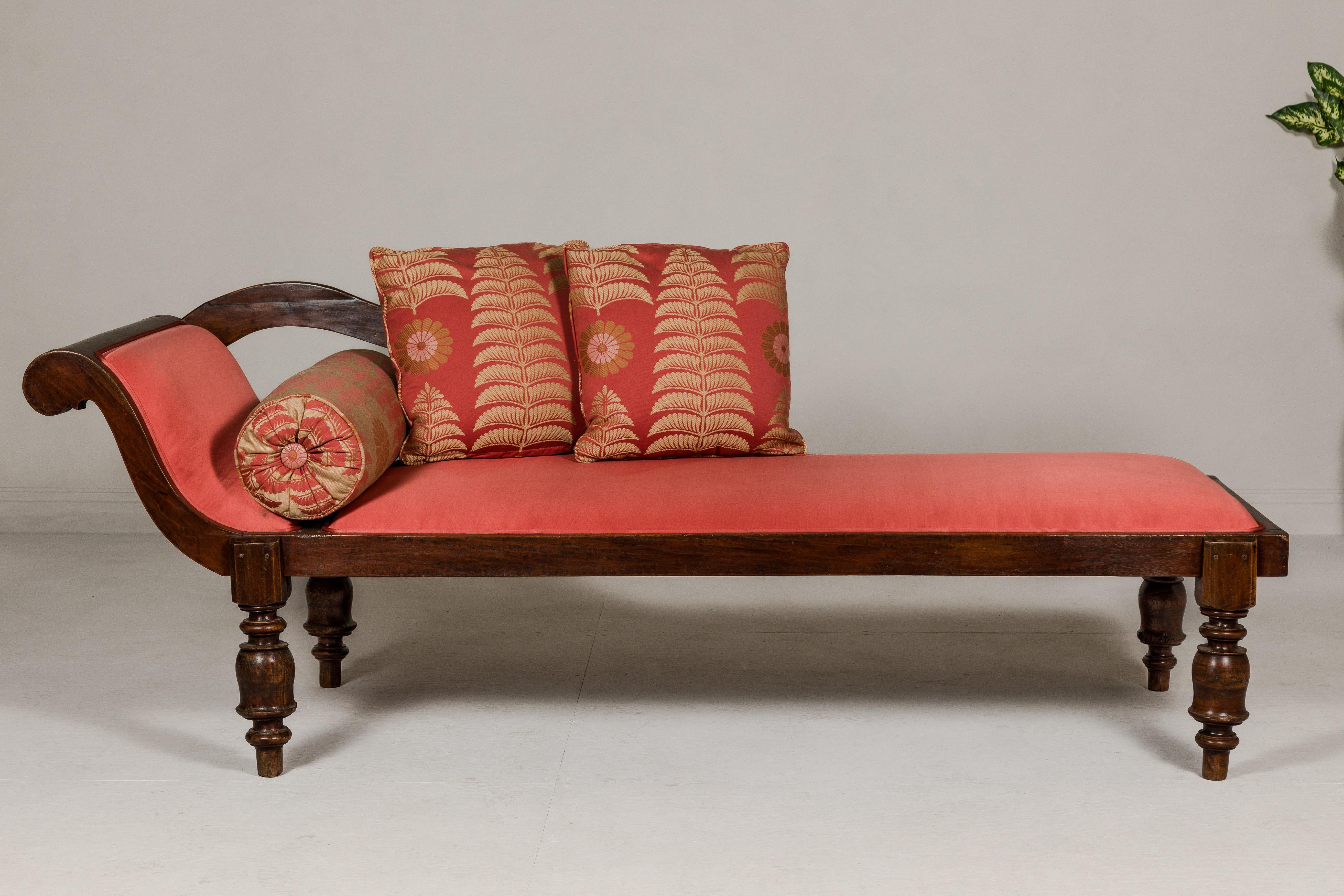 An antique Récamier style wooden daybed with silk fabric cushion, out-scrolling back and turned legs. This antique Récamier-style wooden daybed is a testament to timeless elegance and comfort. Its design exudes sophistication and refinement, making