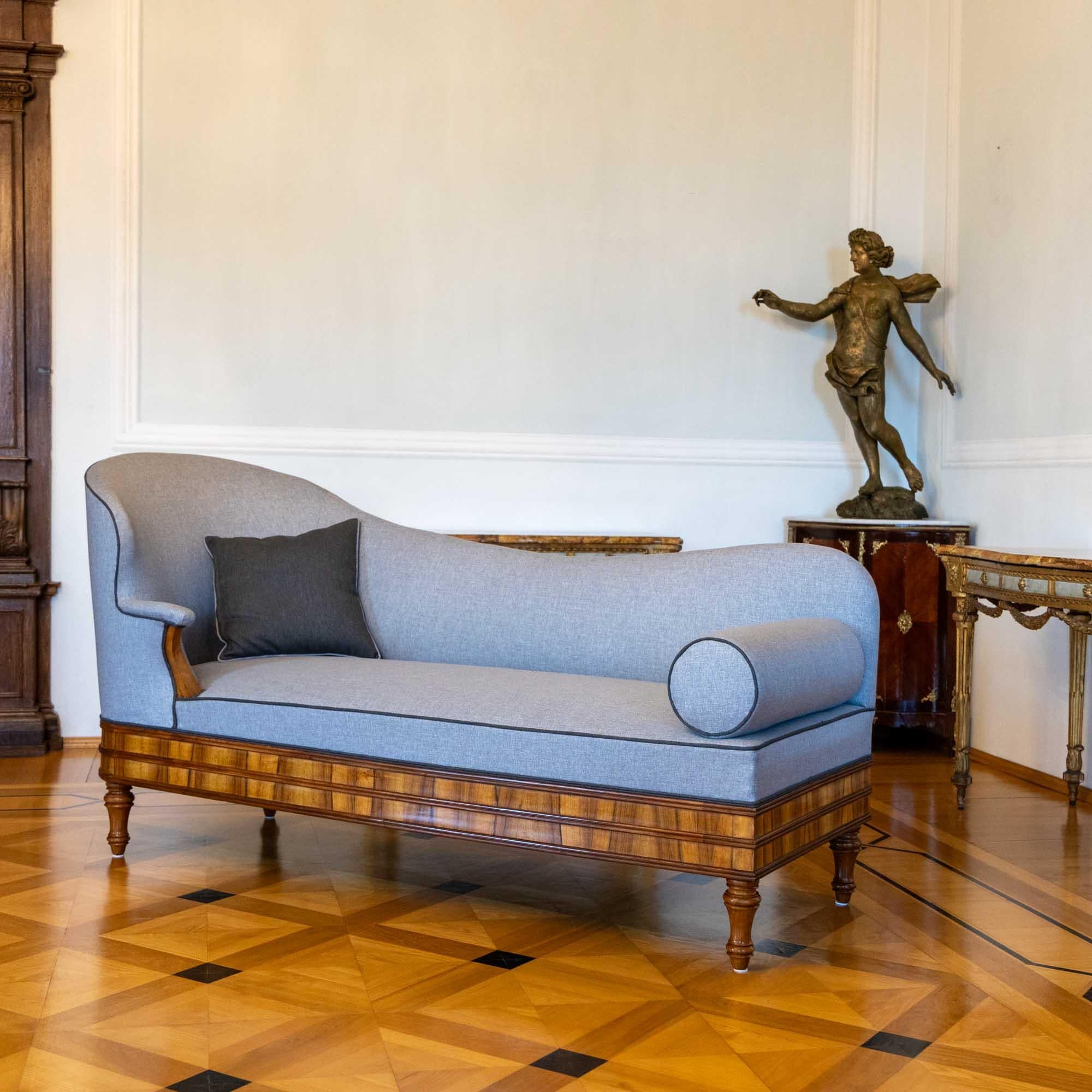 Large recamiere with light gray cover and walnut veneered frame. The straight frame is accentuated with horizontal profile strips and rests on baluster feet. The recamiere has an elegant character and has been completely polished, reupholstered and