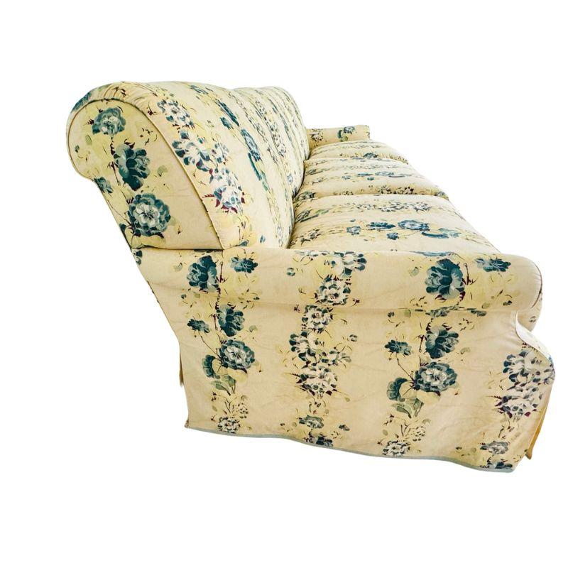 An elegant custom three-cushion sofa, a timeless addition to any living space. Upholstered in a luxurious floral chintz Tillet fabric, it boasts a creamy yellow ground adorned with a charming blue and yellow floral stripe design. The narrow flared