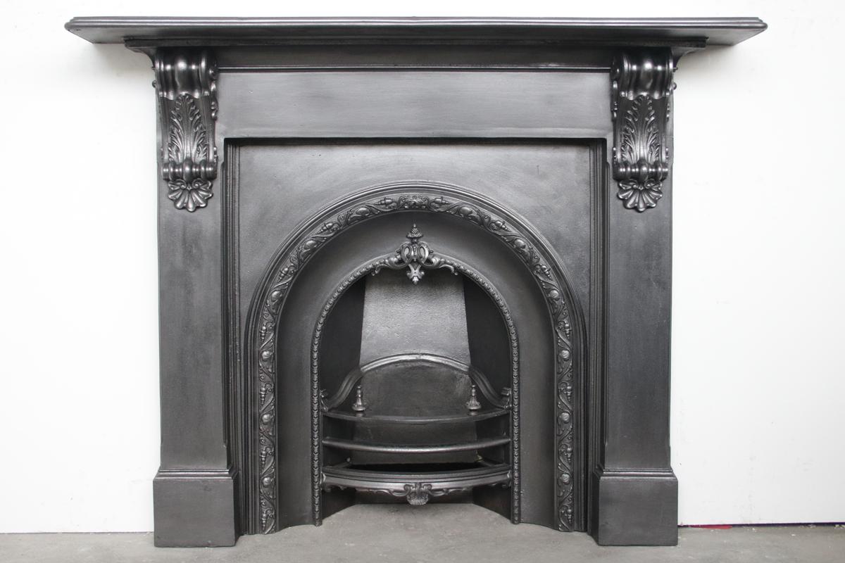 Reclaimed 19th century cast iron fireplace surround of simple form with well cast corbels supporting the shelf, circa 1870. Finished with traditional black grate polish.
Pictured with an original Victorian arched cast iron grate and unusual curved