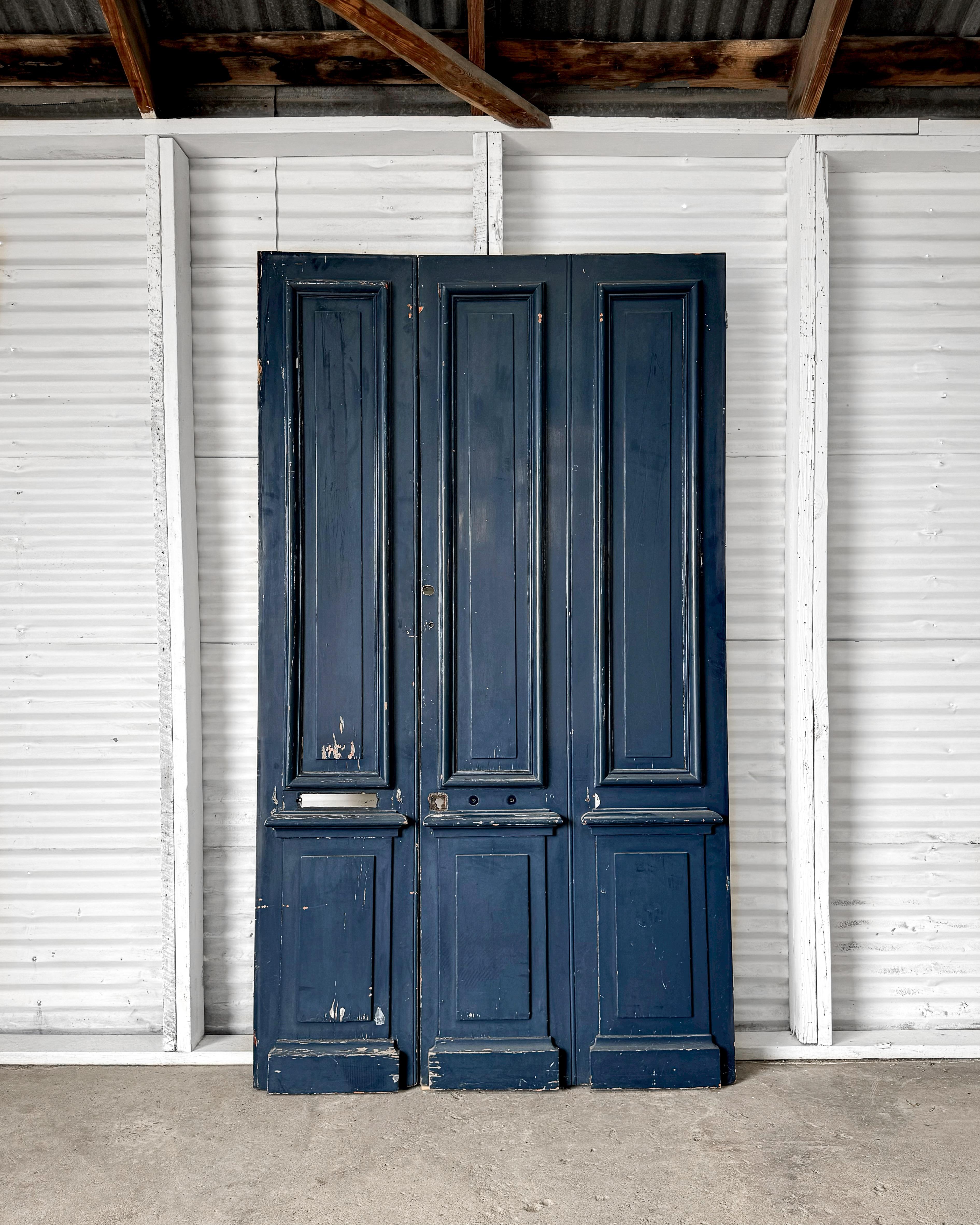 This striking pair of 19th-century French exterior doors, salvaged from the entry of a traditional French home, brings history and character to any space. The doors feature raised panels with finely detailed beveled trim, highlighting the era's