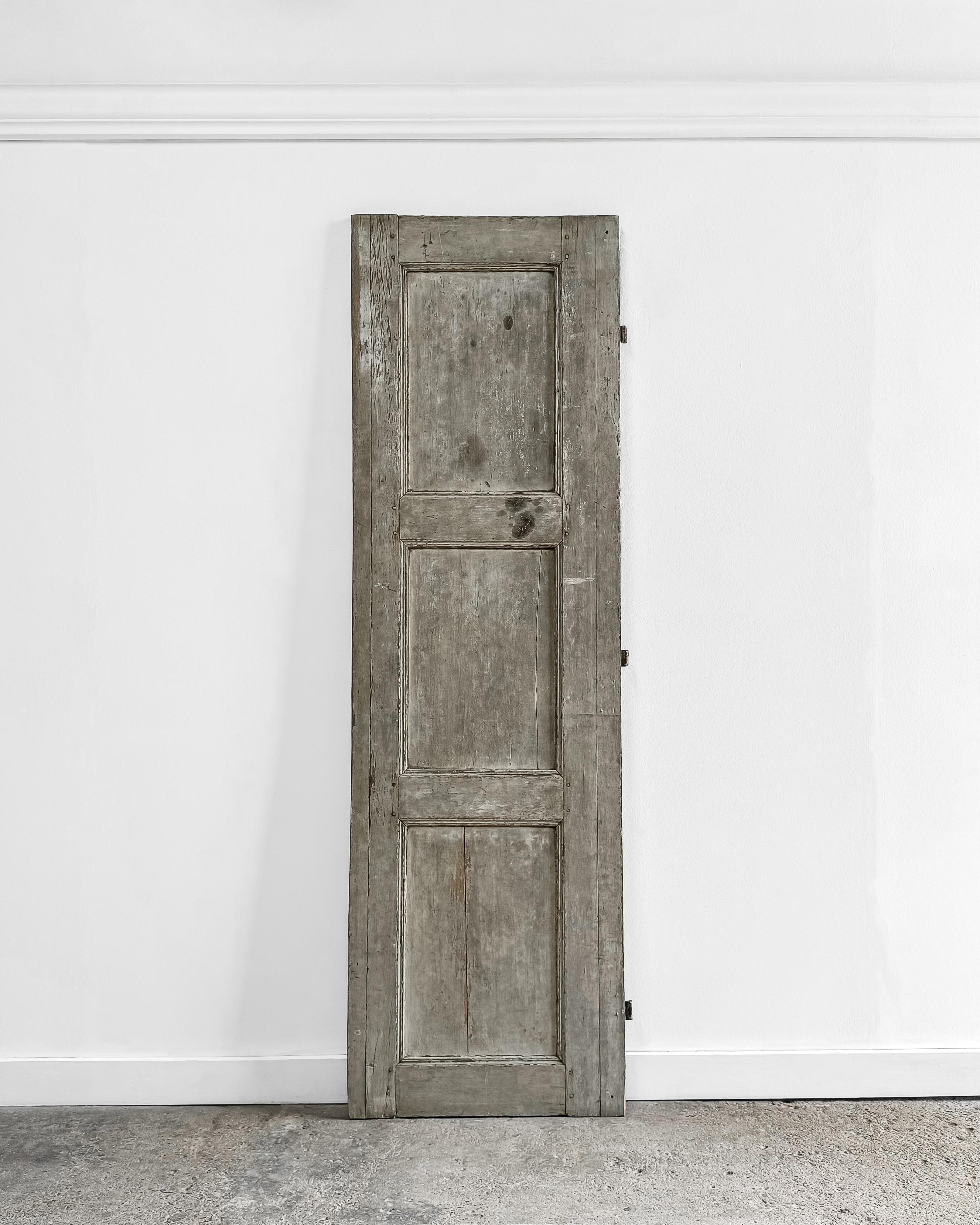 A charming reclaimed French shutter featuring grooved beveled trim detailing and its original sage-gray paint. This beautiful piece can be installed to enclose a cupboard, offering a unique and stylish touch to your storage solutions. Alternatively,