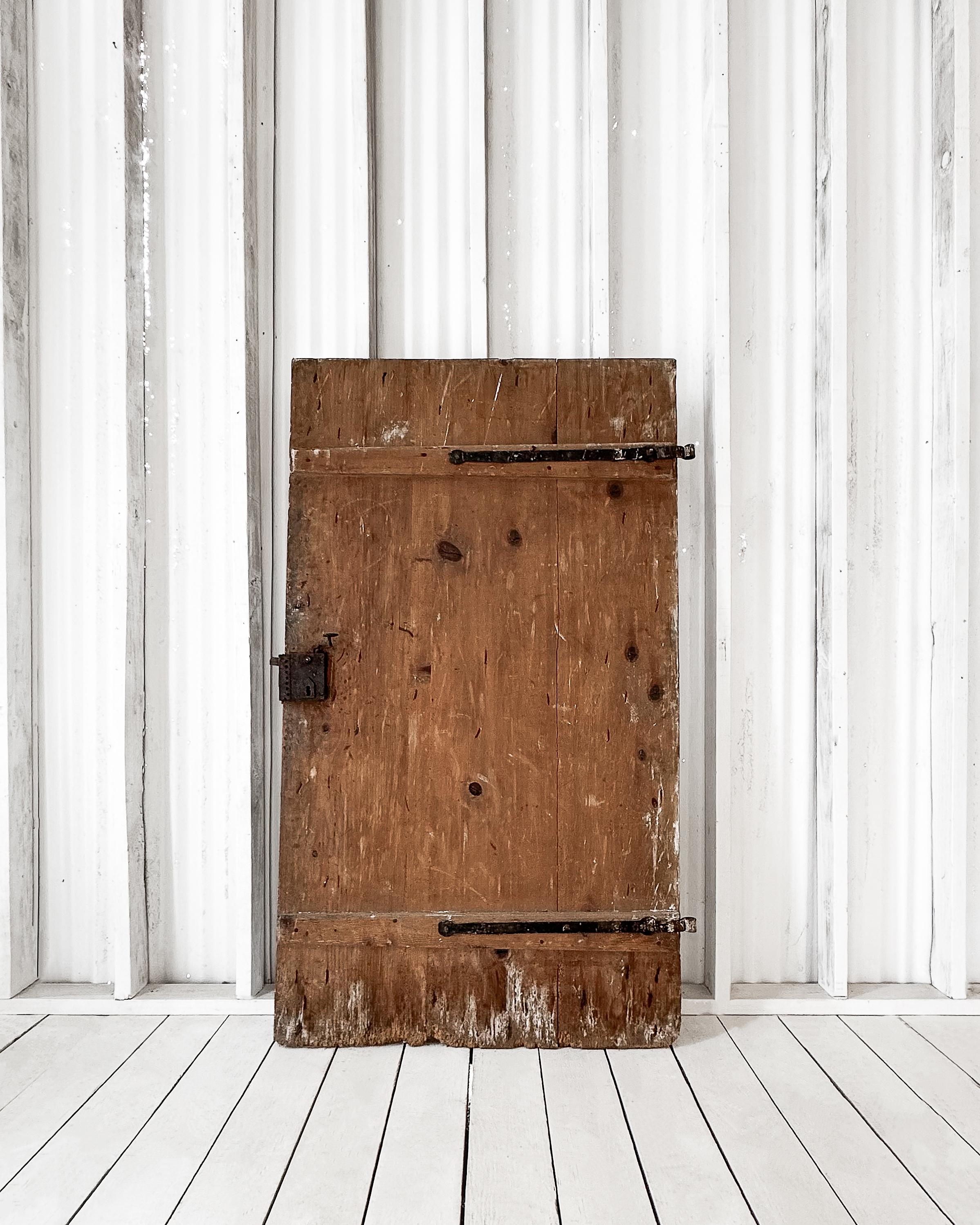 Porta di una casa colonica americana recuperata da una proprietà nelle campagne dell'Ohio. Le tavole di pino piallate a mano con chiodi quadrati e chiodini a vista testimoniano la sua onesta costruzione, mentre le tracce di imbiancatura alla base