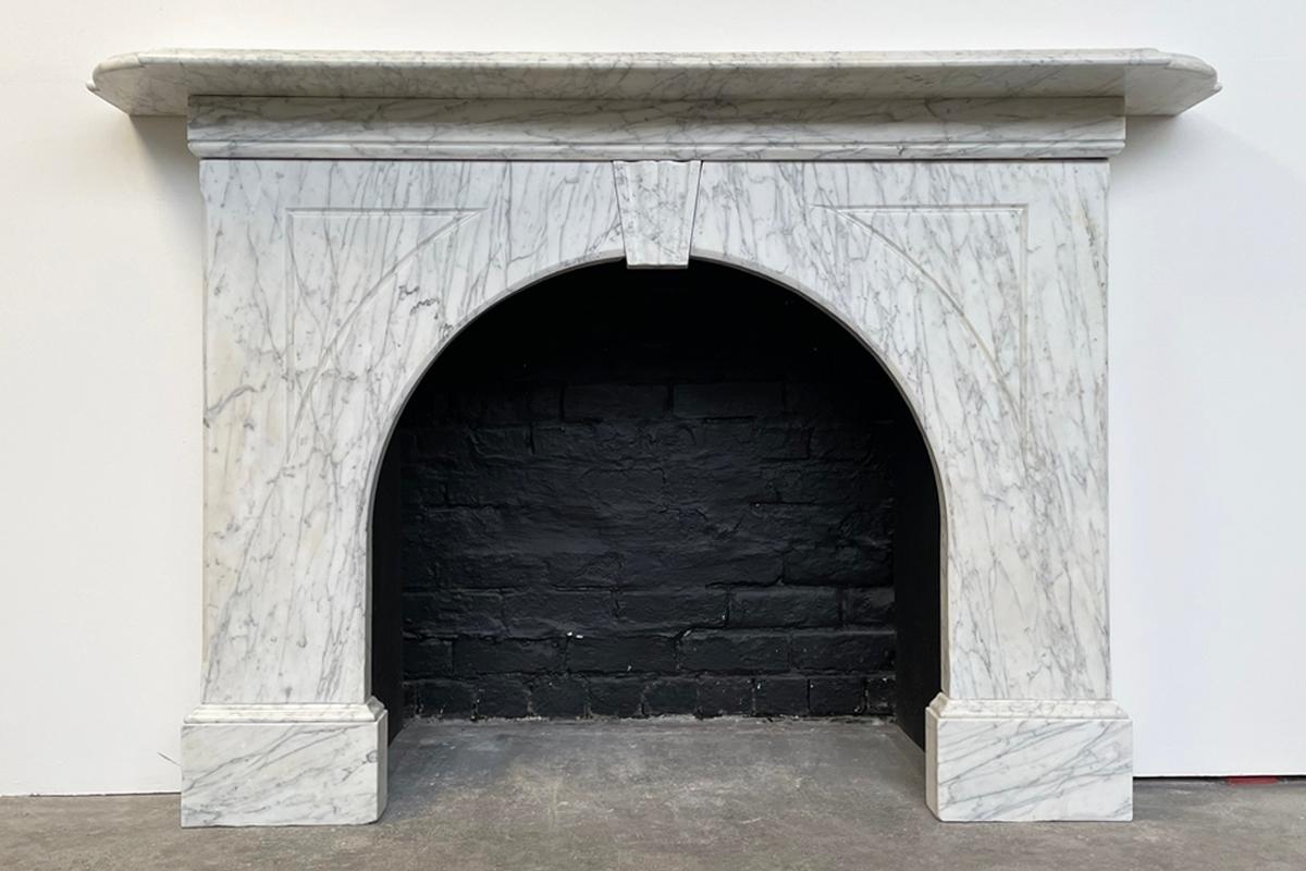 An arched Victorian Carrara marble fireplace surround of good proportions. A full length frieze sits below a deep mantle with an ogee-moudled edge and shaped corners above a carved keystone and flutes to the arched spandrels. Circa 1860.

For
