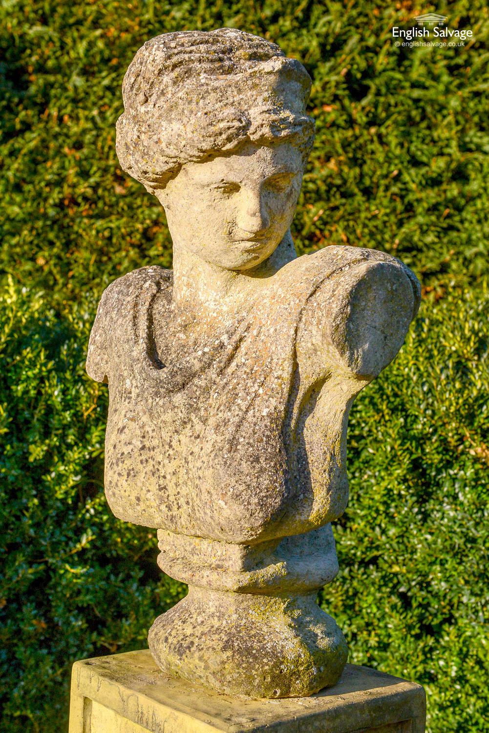 Salvaged composition stone bust of classical Greek figure looking downwards. Near lifesize. Attractively weathered with moss and lichen patina present and softening to the definition of the figure. Surface pitting and chips commensurate with age,