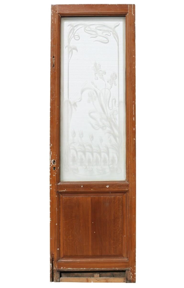 A salvaged door of pine construction featuring a large etched glass panel.