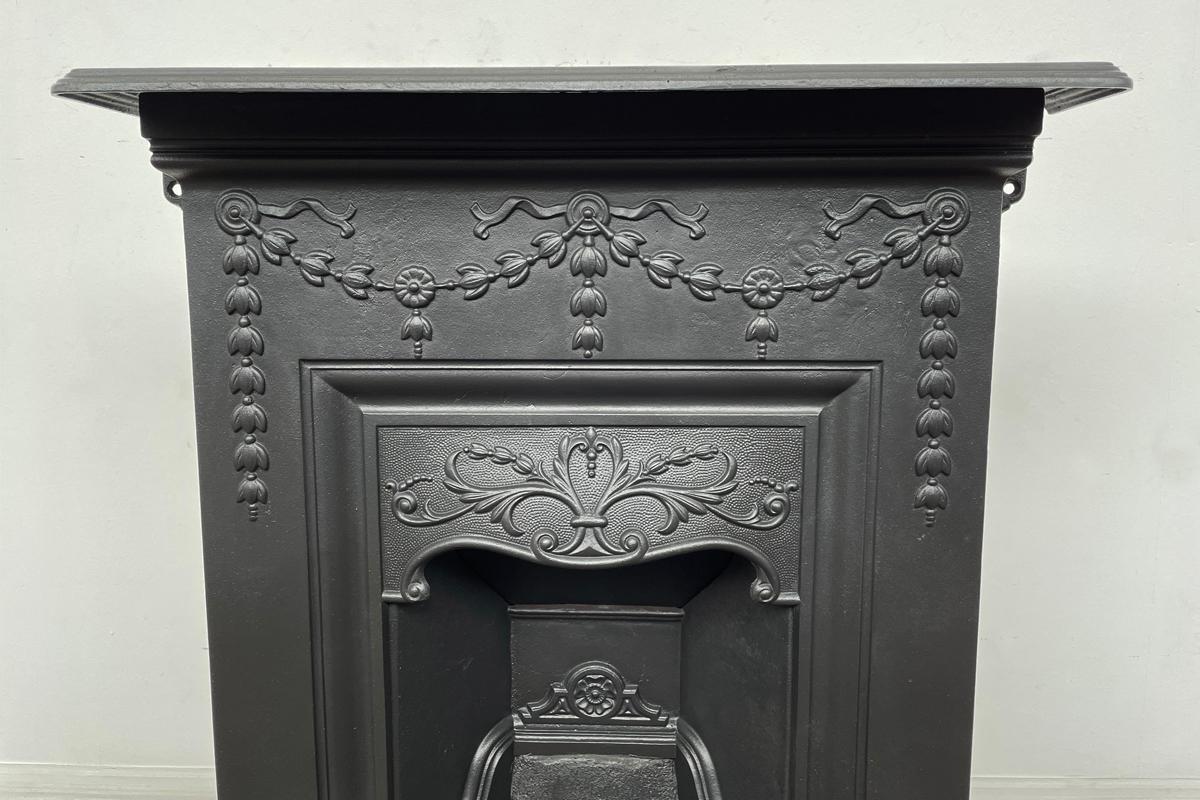 Small reclaimed Edwardian cast iron combination fireplace in a classical manner, decorated with swags ribbons and bellflowers. Dated 1908.

Finished in heat resistant matte black paint finish.

For detailed sizes see the size diagram in the